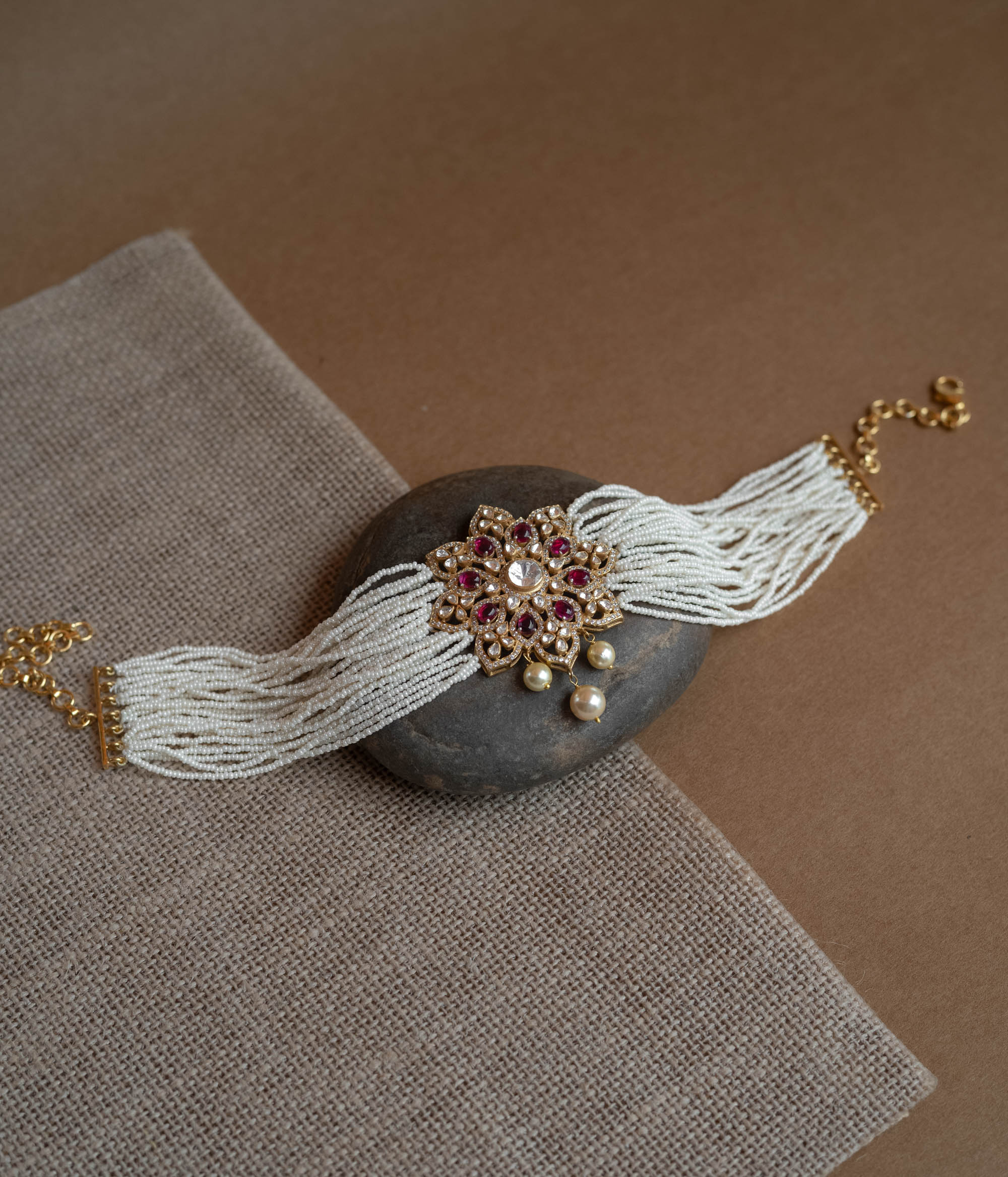 A divine blossom of Polki and pearls, kissed by red starlight, gracing your neck with celestial charm.