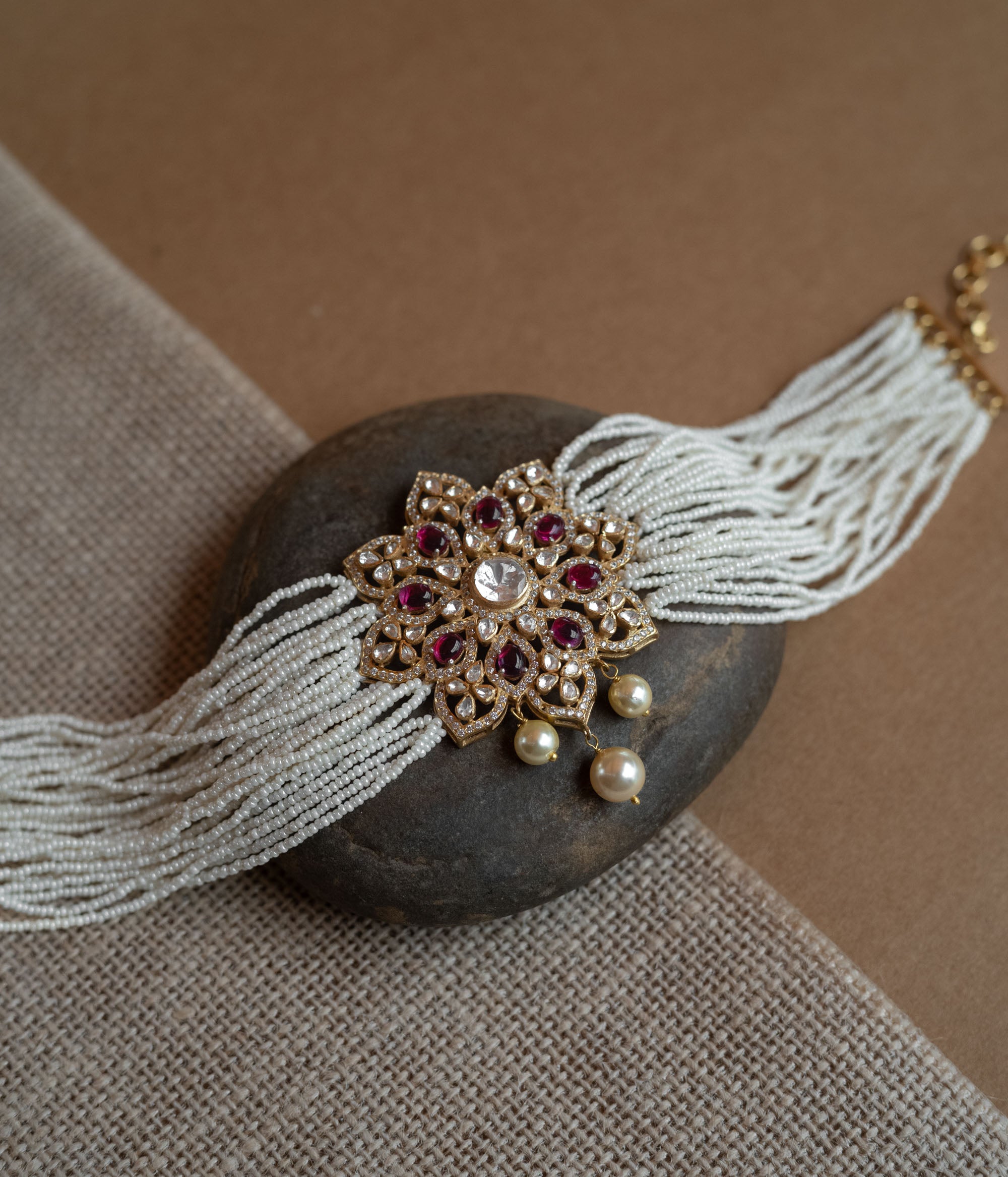 A divine blossom of Polki and pearls, kissed by red starlight, gracing your neck with celestial charm.