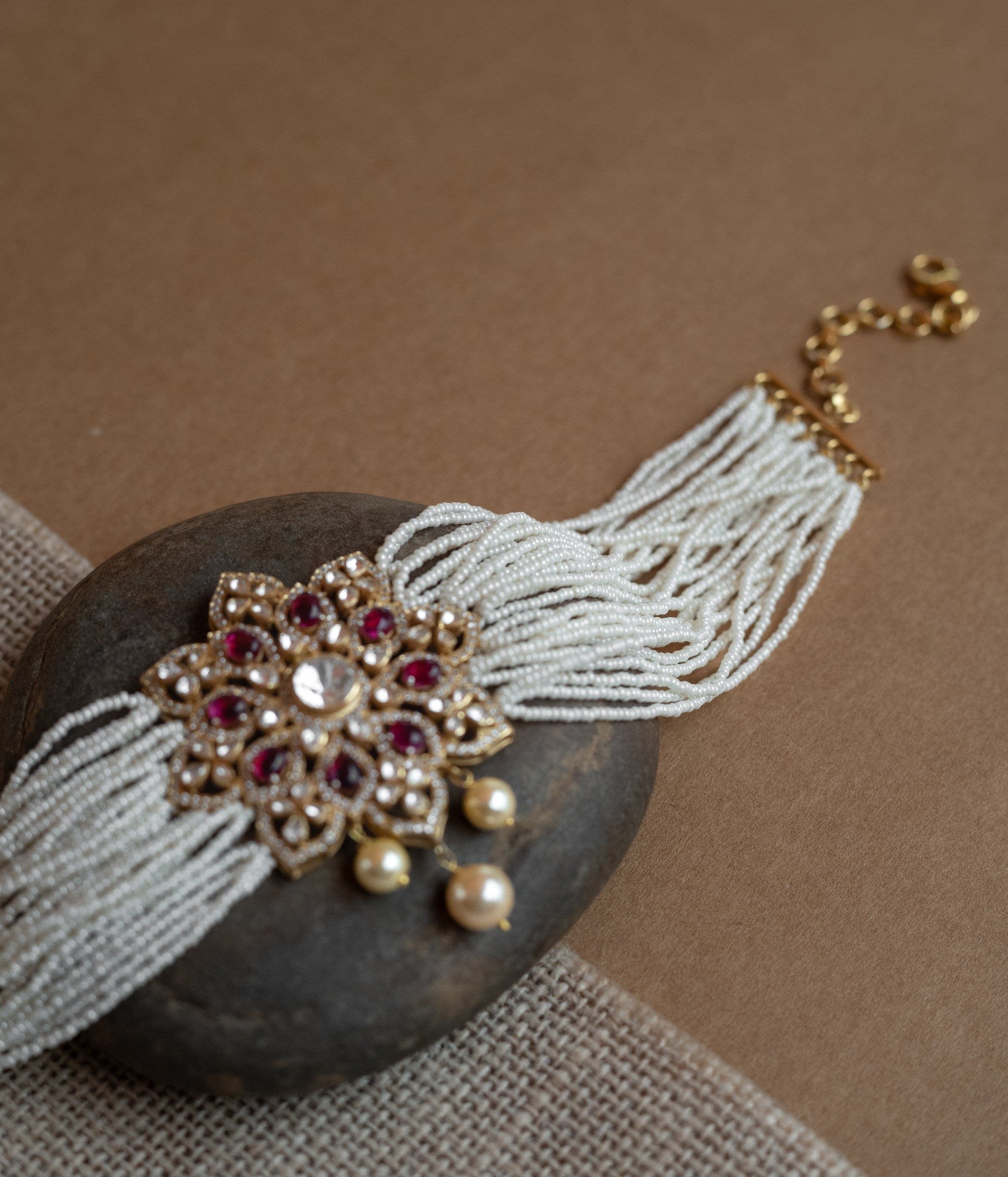 A divine blossom of Polki and pearls, kissed by red starlight, gracing your neck with celestial charm.