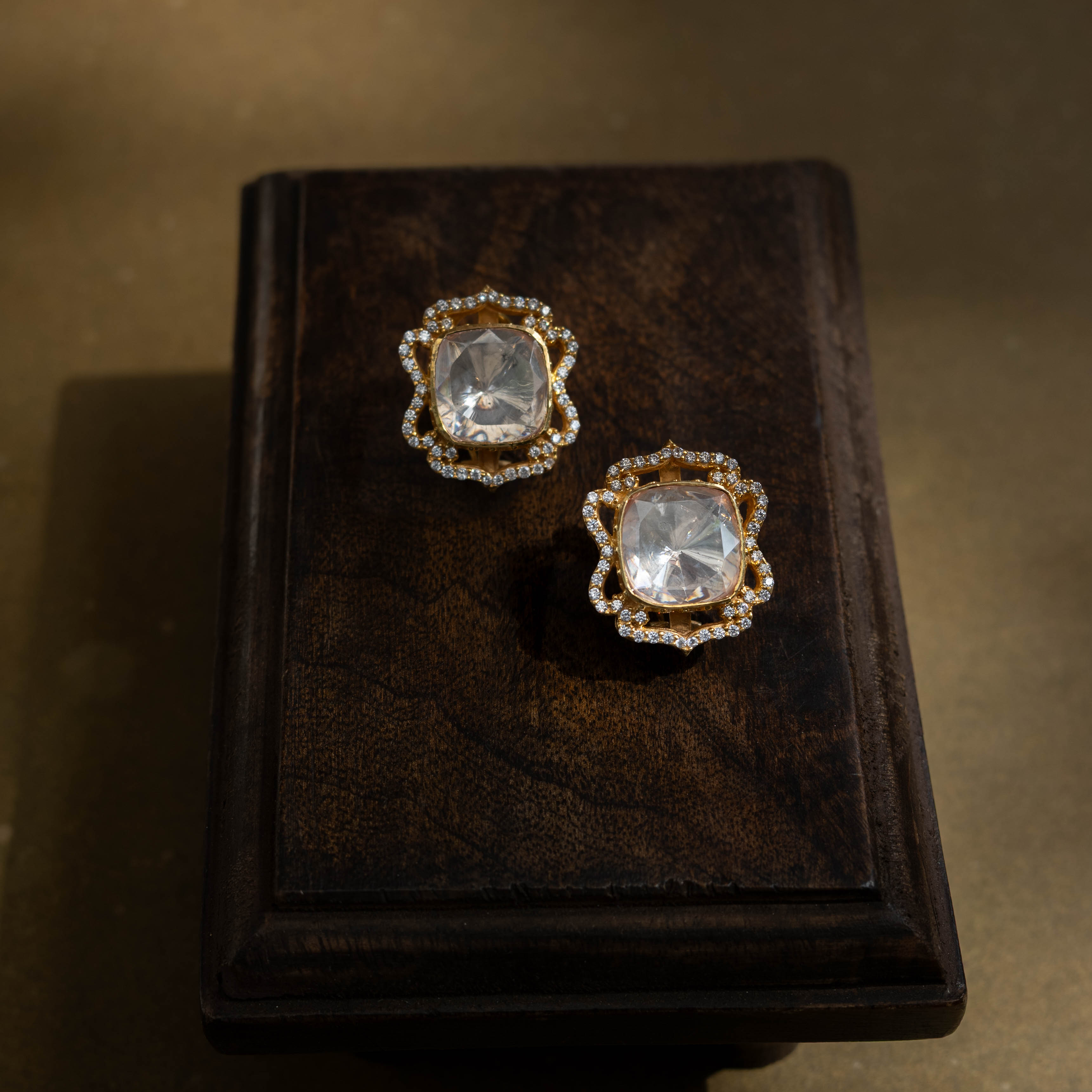 Large, intricate earrings with a studded top and a dangling motif, all set with clear stones.