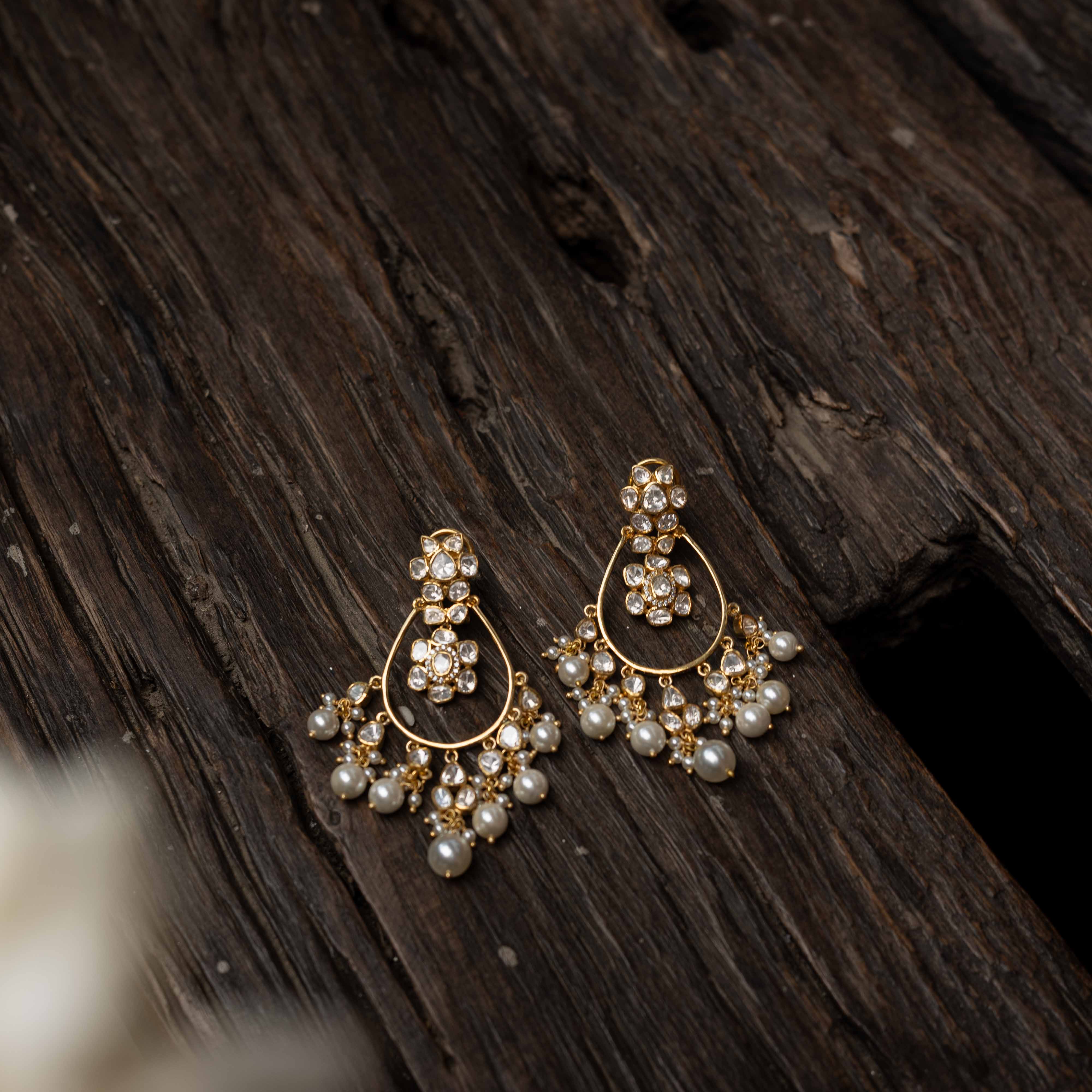 Intricate jhumka earrings with clear stones and dangling pearls.