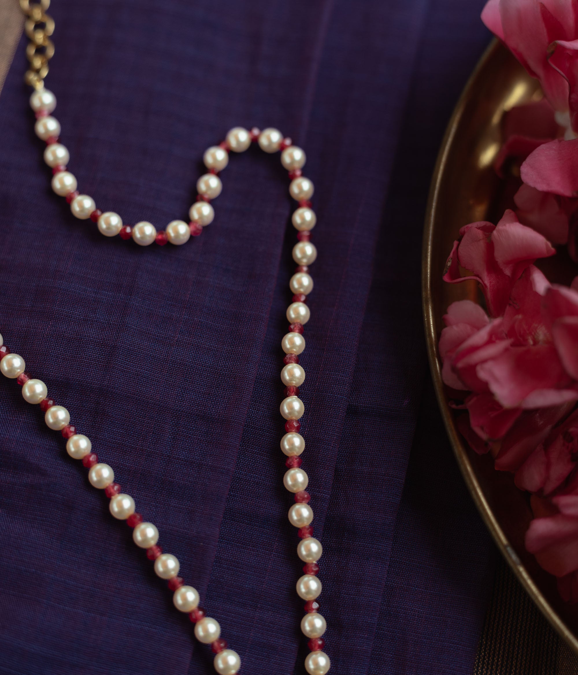 Floral Polki necklace with emerald center, red Kundan accents, and pearl string.