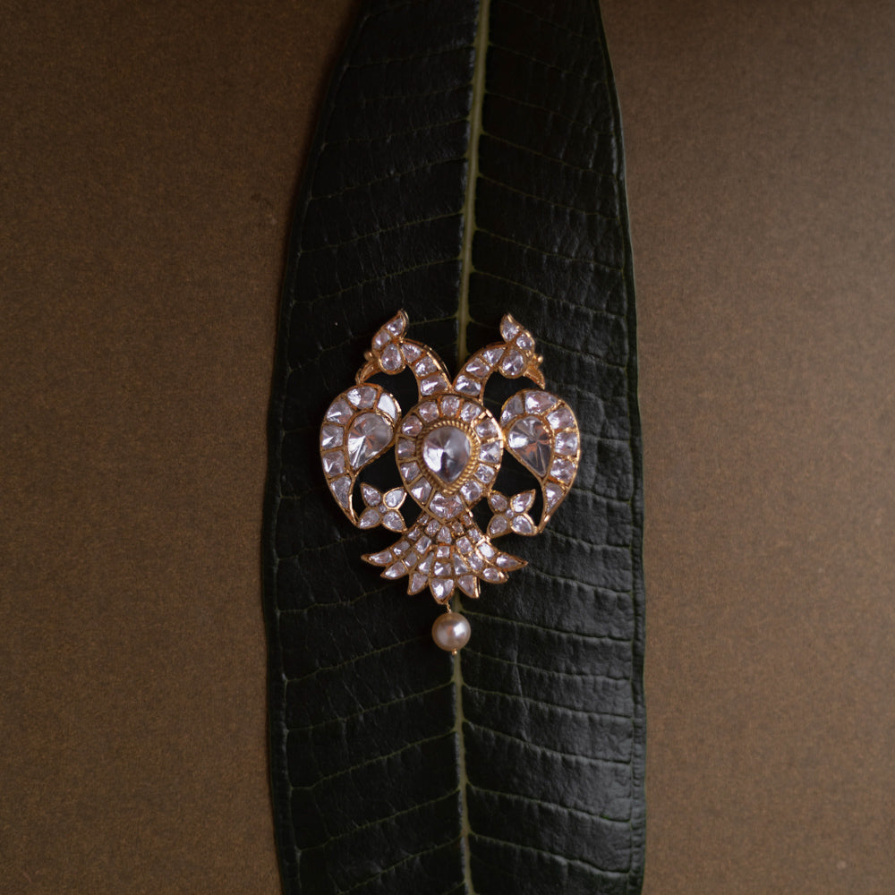 Antique gold pendant featuring twin peacocks, set with moissanite polki stones, and a single pearl drop.