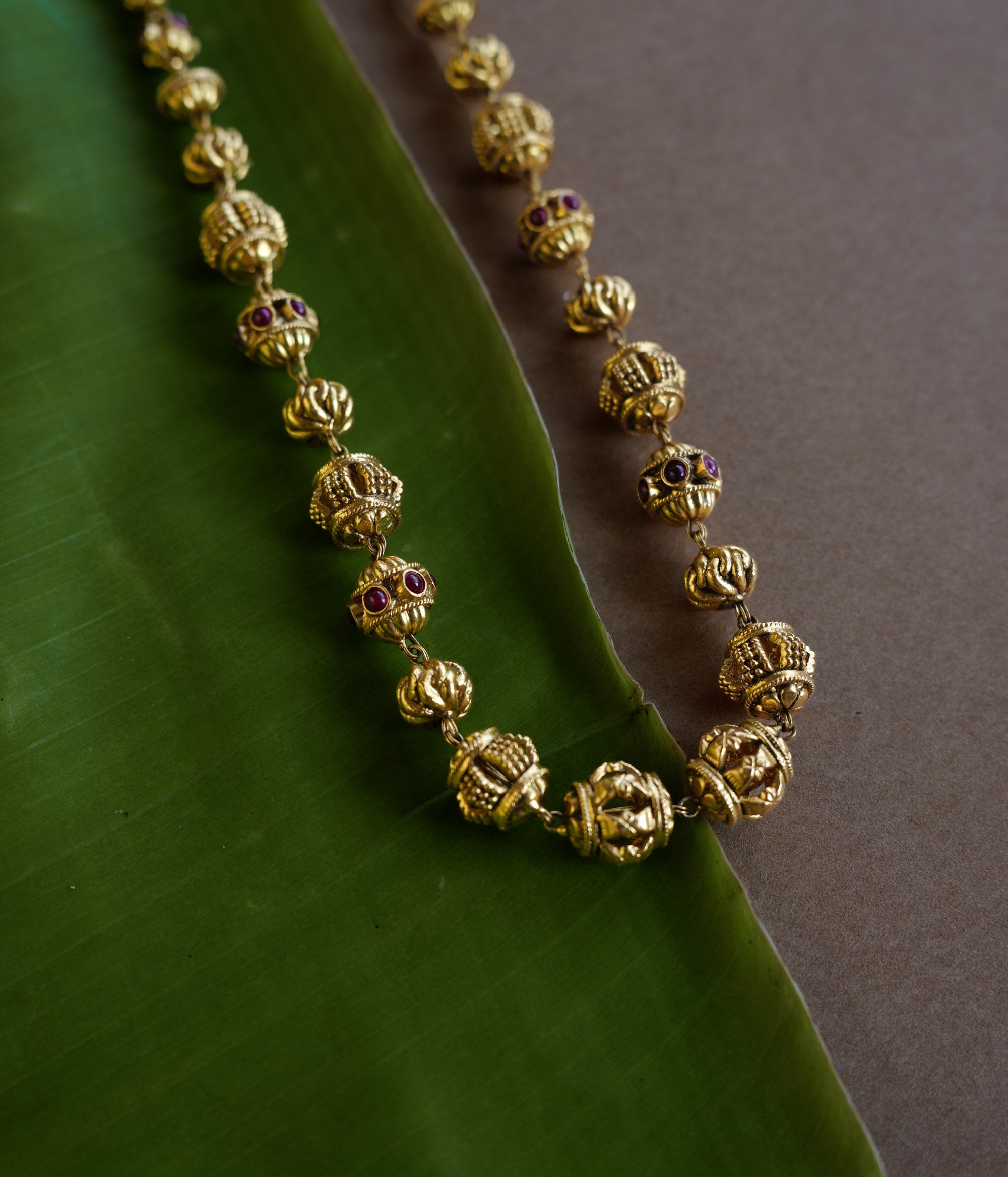 Golden beaded chain with ornate spherical motifs and red spinel accents from the Plain Collection.