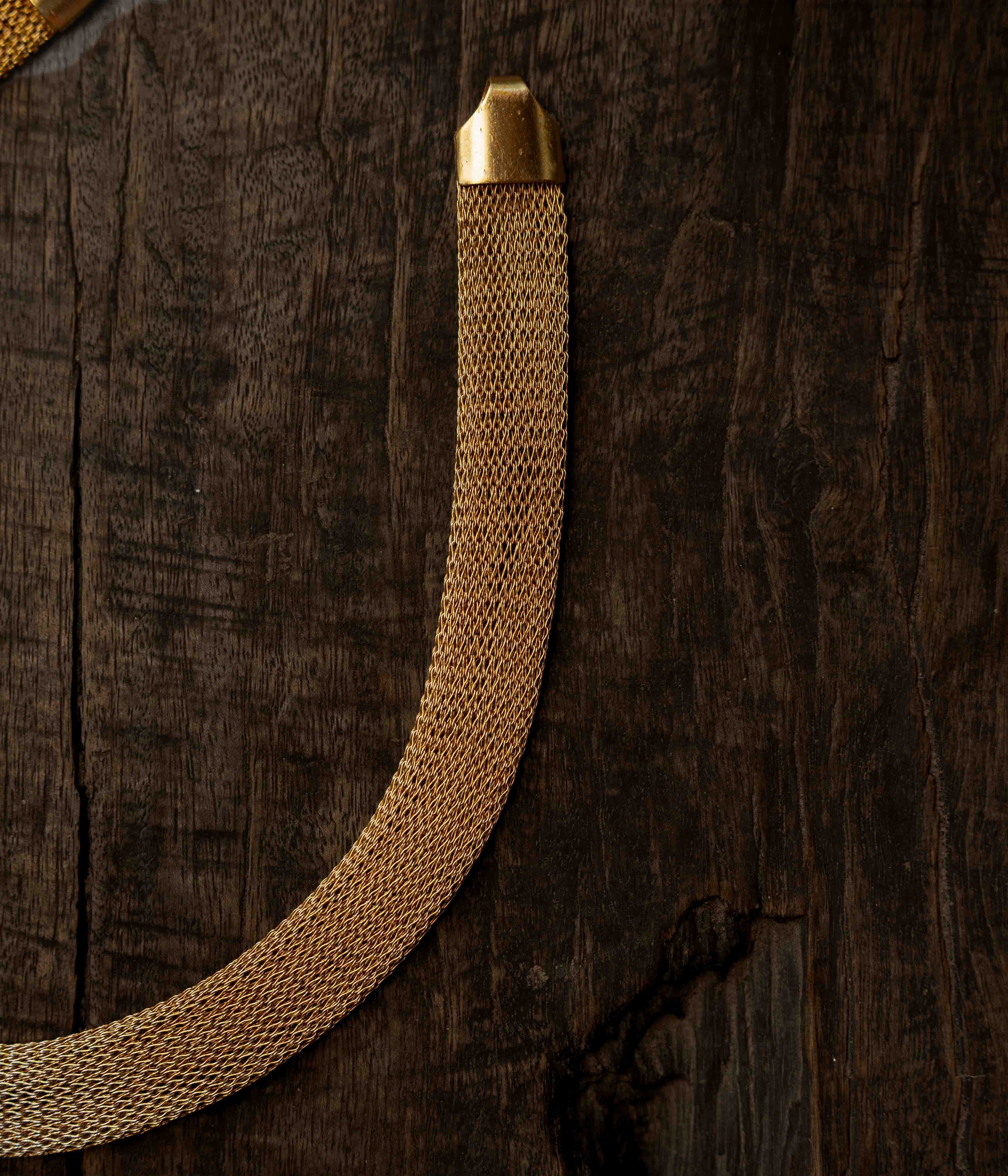 A multi-strand long chain made of small, gold-toned beads.