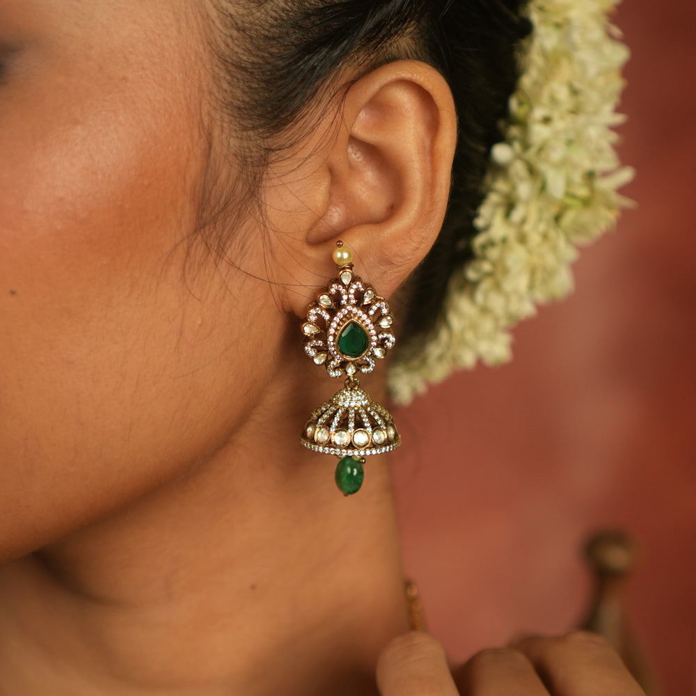 Victorian elegance reborn! Moissanite jhumkas with emerald hearts, encircled by polki and CZ stones, exude timeless allure with every sway.