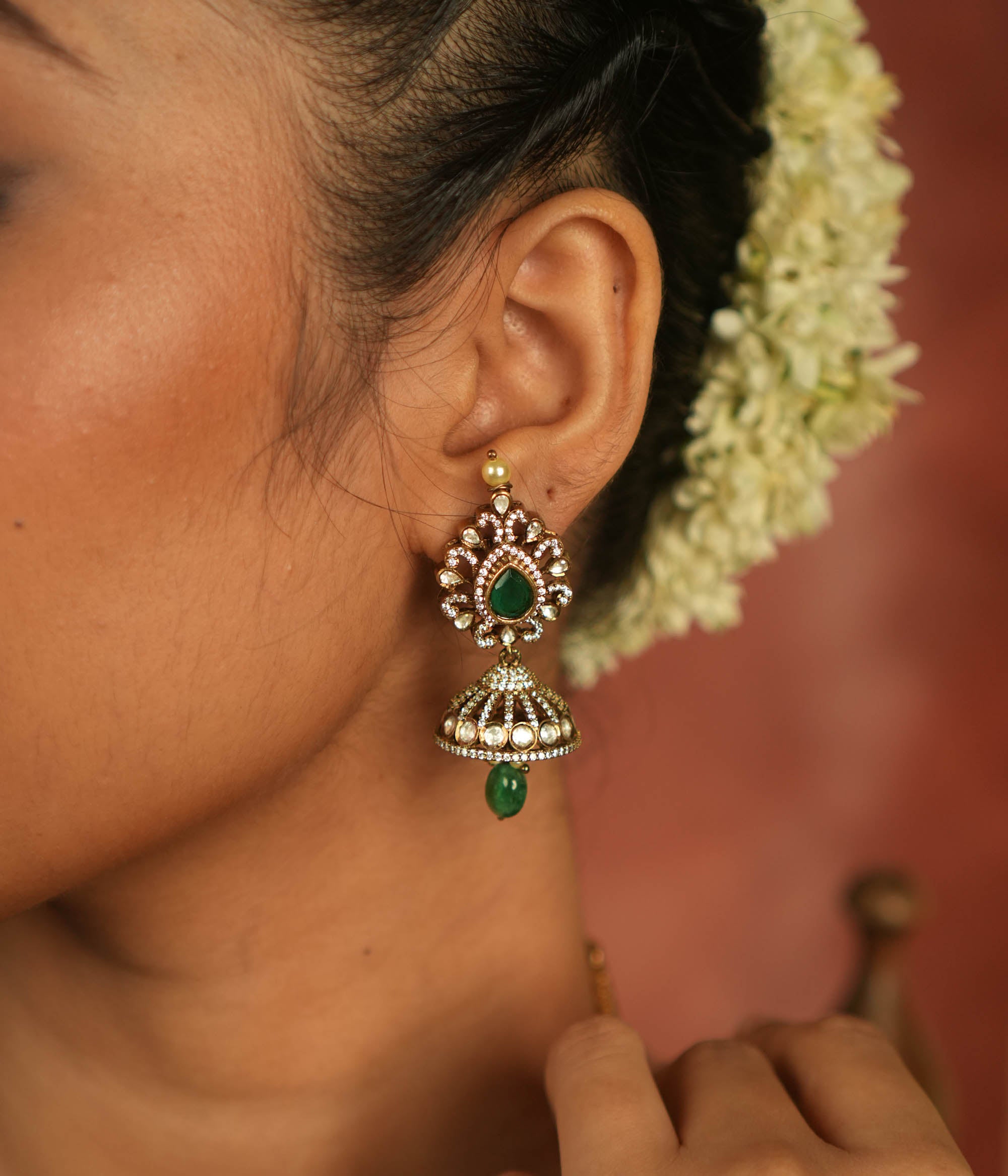 Victorian elegance reborn! Moissanite jhumkas with emerald hearts, encircled by polki and CZ stones, exude timeless allure with every sway.