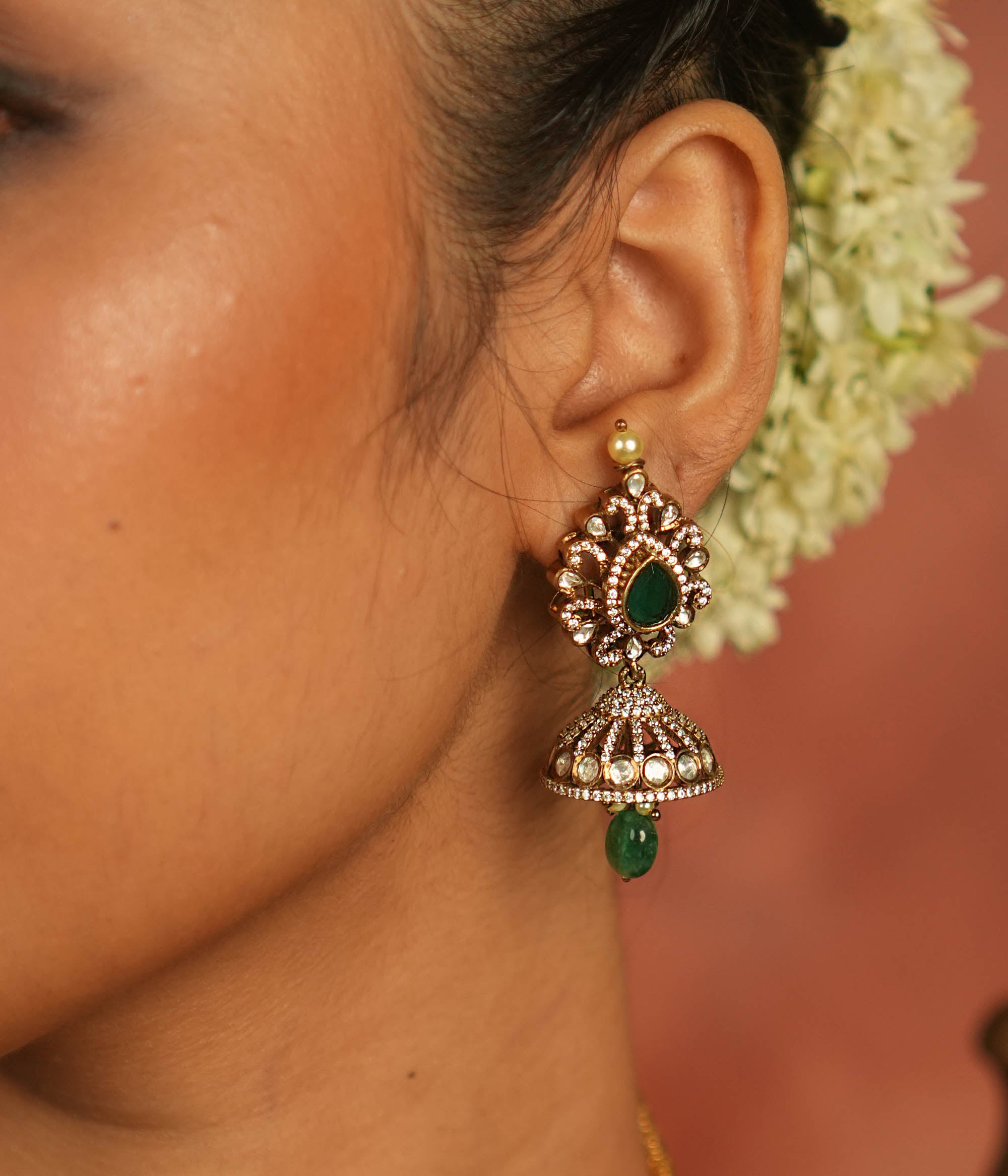 Victorian elegance reborn! Moissanite jhumkas with emerald hearts, encircled by polki and CZ stones, exude timeless allure with every sway.