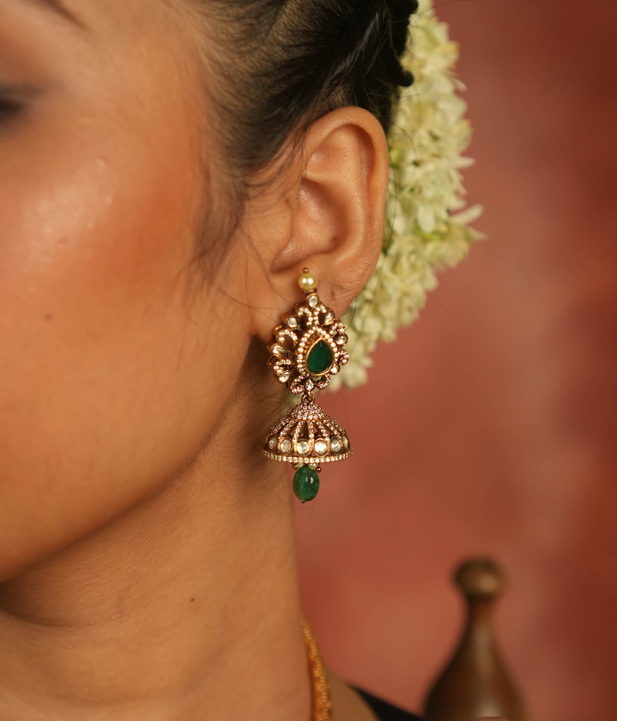 Victorian elegance reborn! Moissanite jhumkas with emerald hearts, encircled by polki and CZ stones, exude timeless allure with every sway.