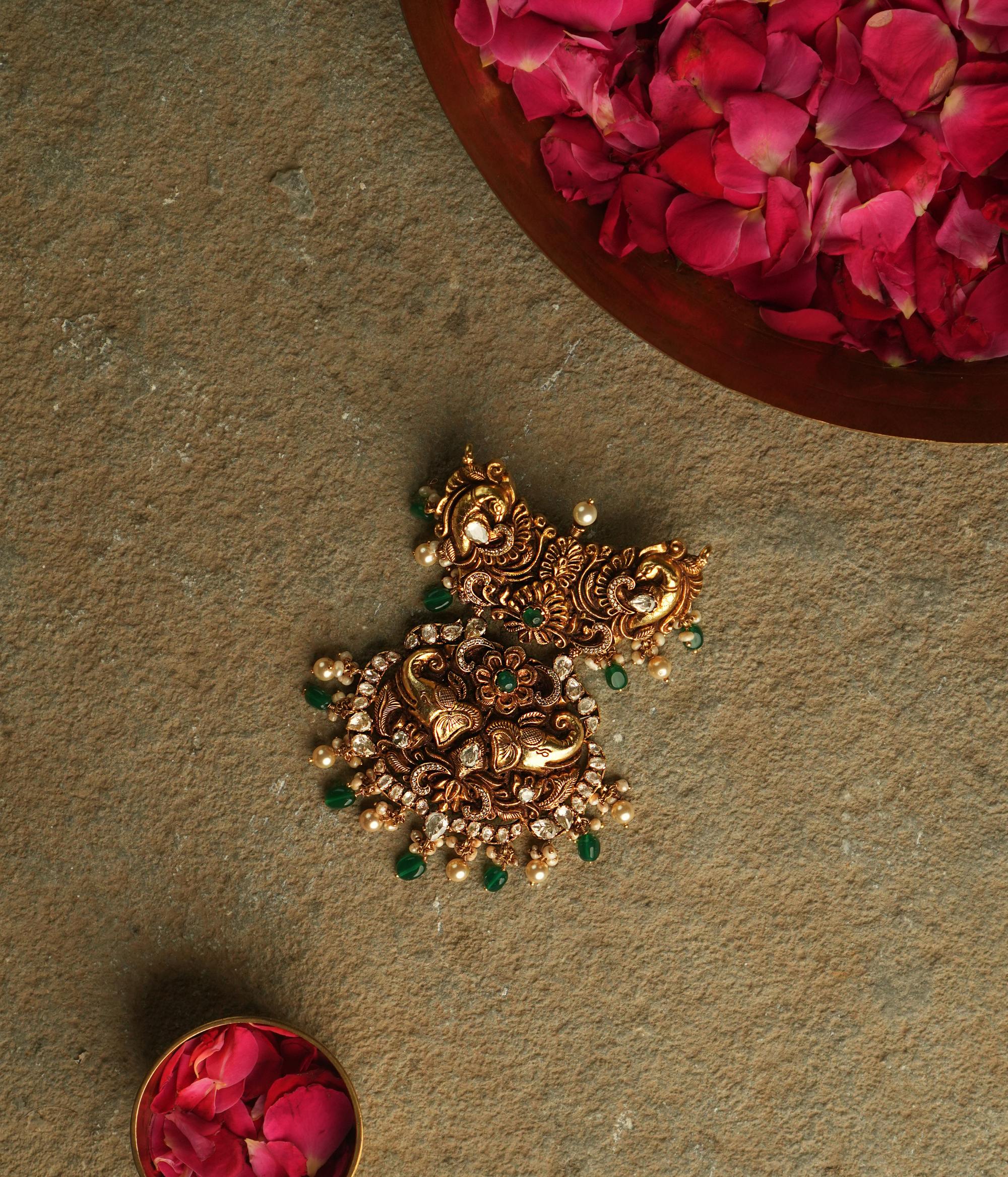 The Nehark Pendant is a mesmerizing fusion of peacock, elephant, and floral motifs, adorned with red, white, and green Kundan stones and golden beads. A timeless masterpiece, it embodies the elegance of ancient traditions, radiating a captivating, mystical glow.