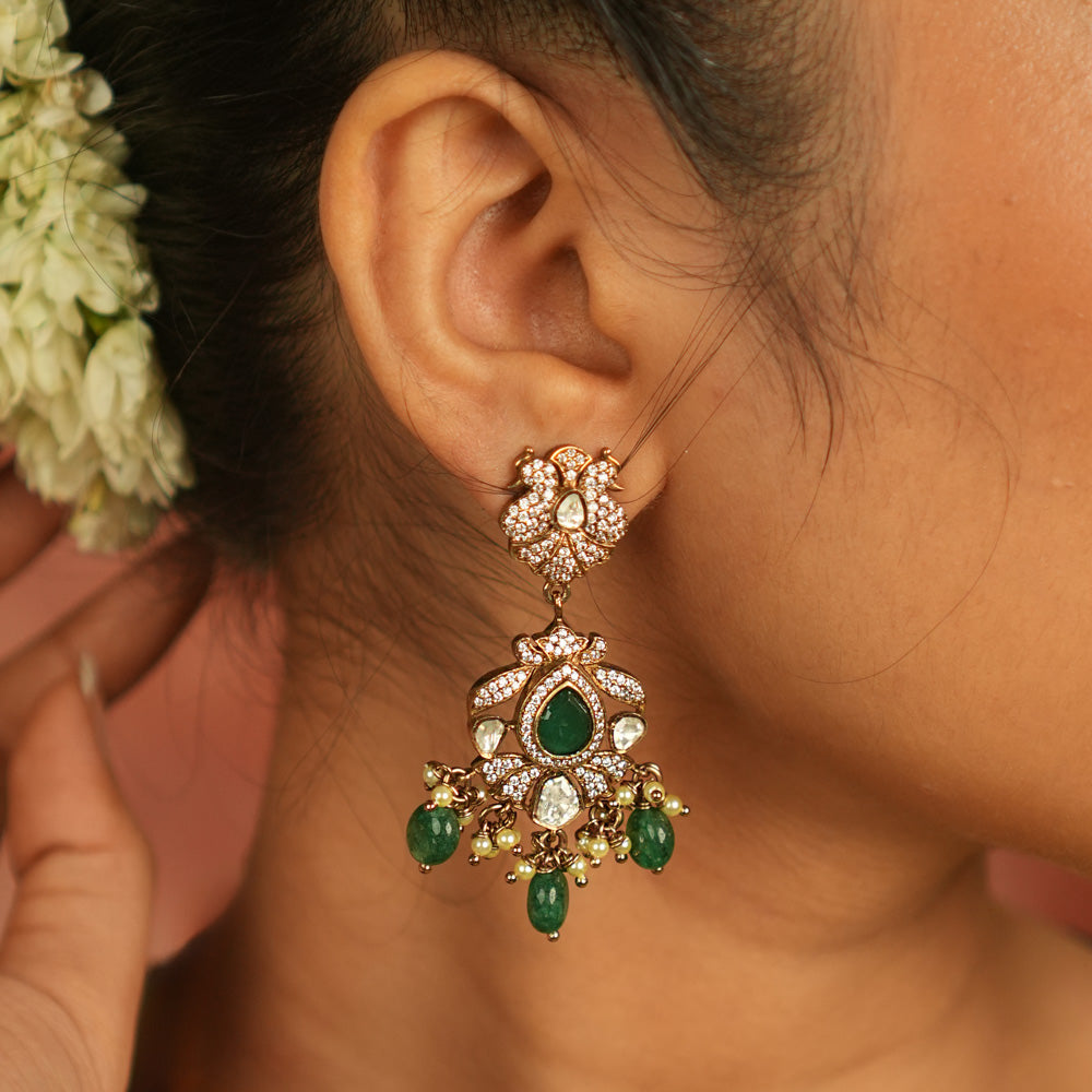Victorian elegance reborn! Peacock-inspired dangler earrings with green gemstones, polki, and CZ stones, adorned with delicate green bead drops, echo timeless beauty and opulence.