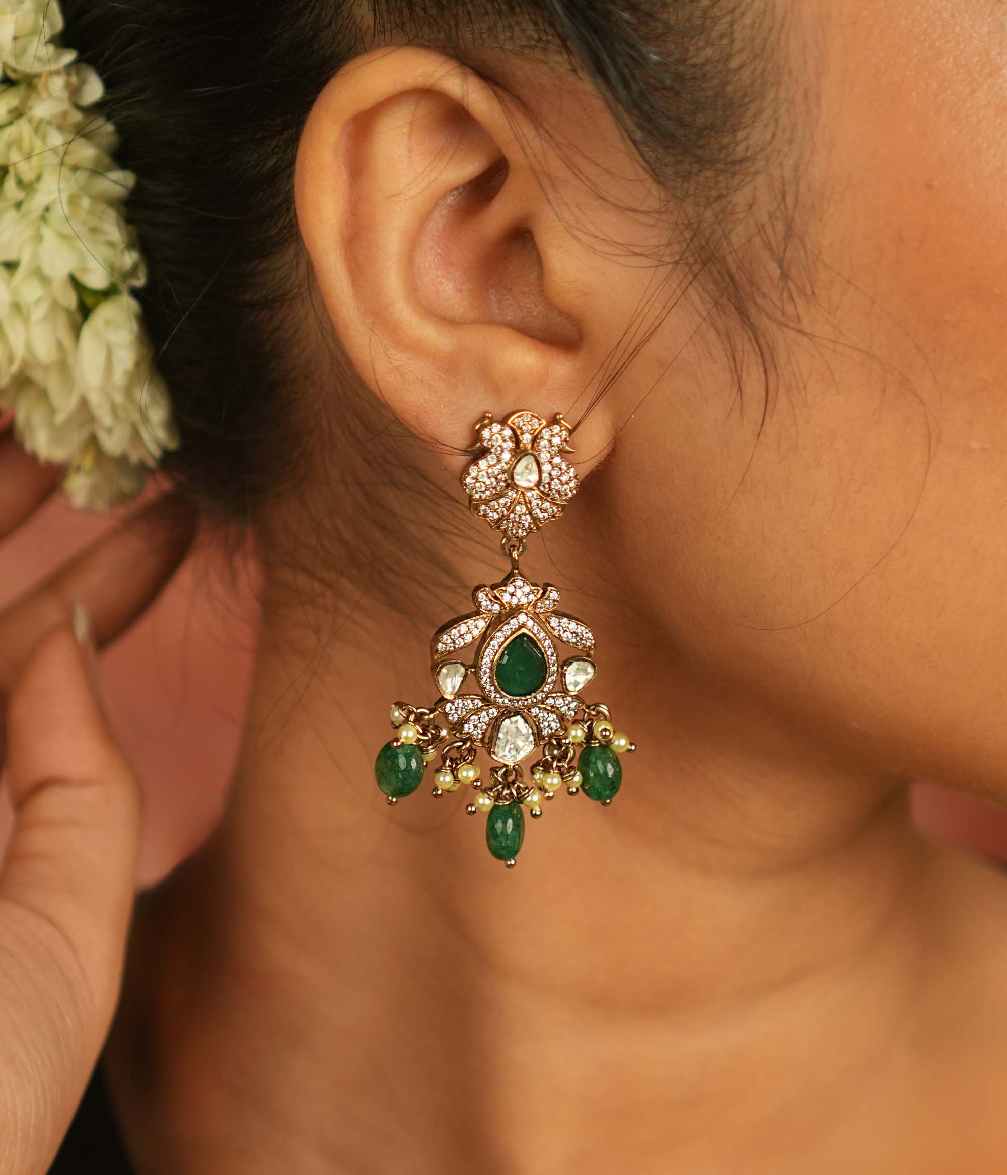 Victorian elegance reborn! Peacock-inspired dangler earrings with green gemstones, polki, and CZ stones, adorned with delicate green bead drops, echo timeless beauty and opulence.