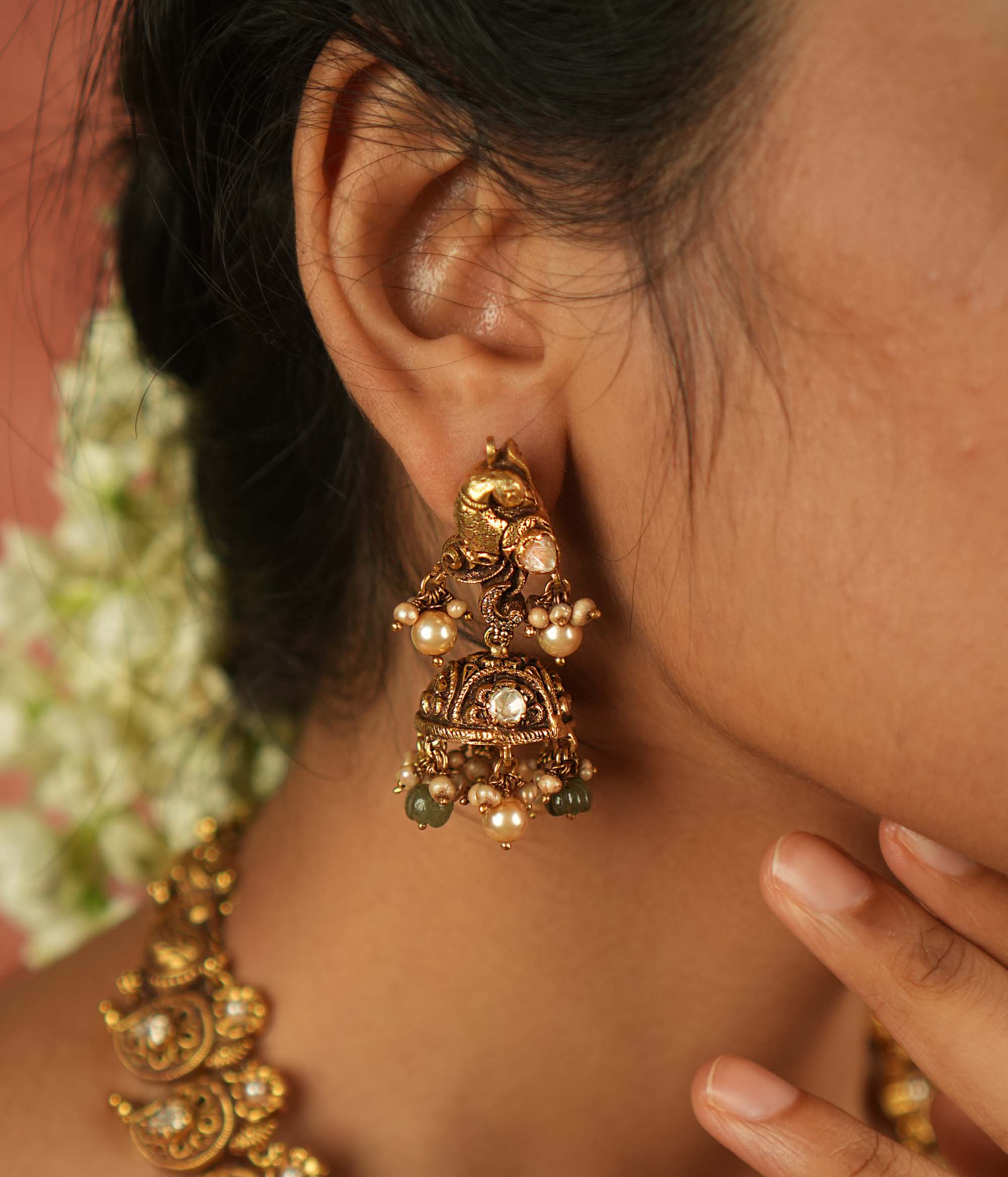 Timeless splendor! These antique gold-plated jhumkas, adorned with a majestic peacock motif, glisten with Polki stones, white pearls, and green beads—echoing regal heritage with every sway.