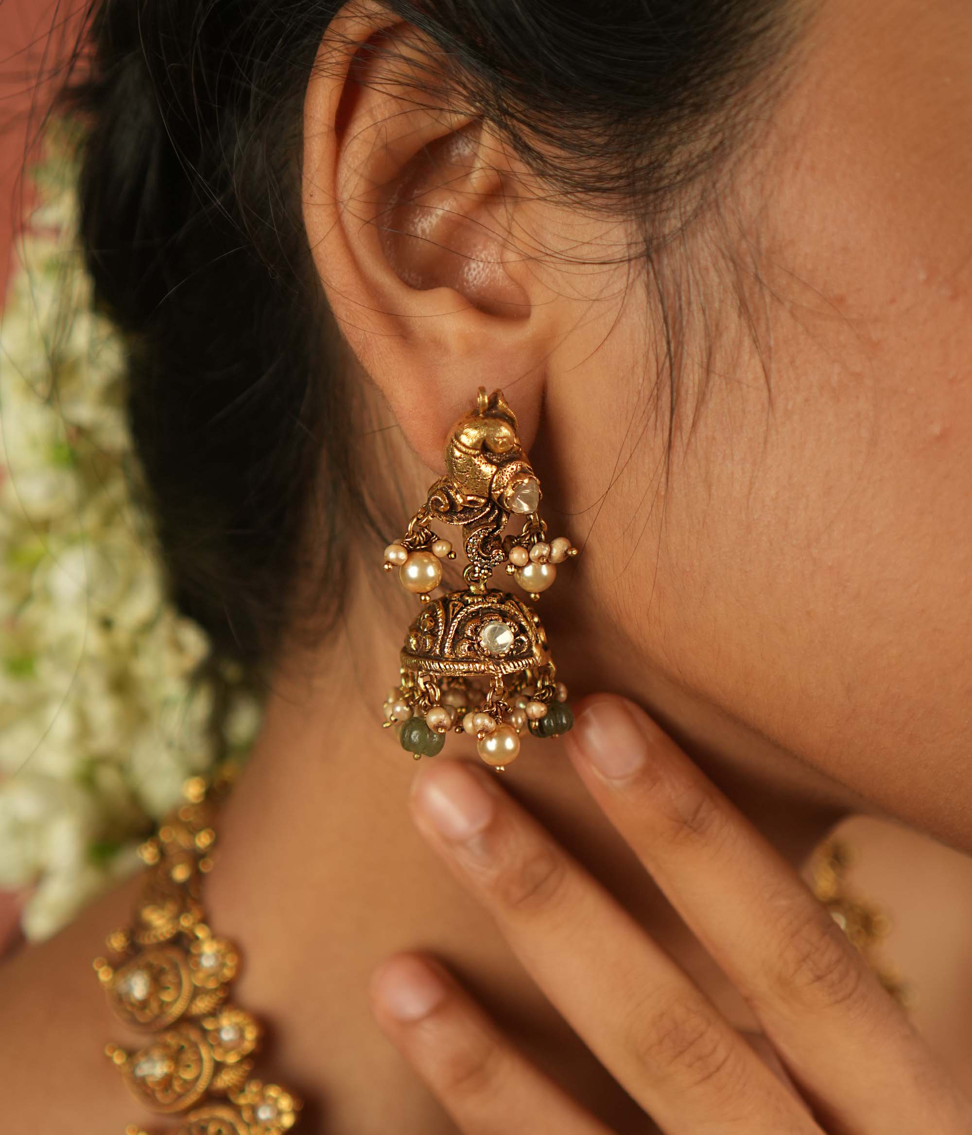 Timeless splendor! These antique gold-plated jhumkas, adorned with a majestic peacock motif, glisten with Polki stones, white pearls, and green beads—echoing regal heritage with every sway.