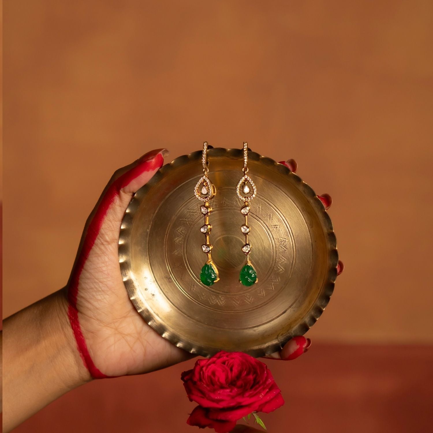 Elegant gold-plated silver push-type drop earrings featuring a dazzling Polki stone at the center, gracefully surrounded by shimmering CZ stones. The design is further enhanced with a vibrant green gemstone, adding a touch of sophistication and timeless charm. Perfect for elevating any traditional or modern ensemble.