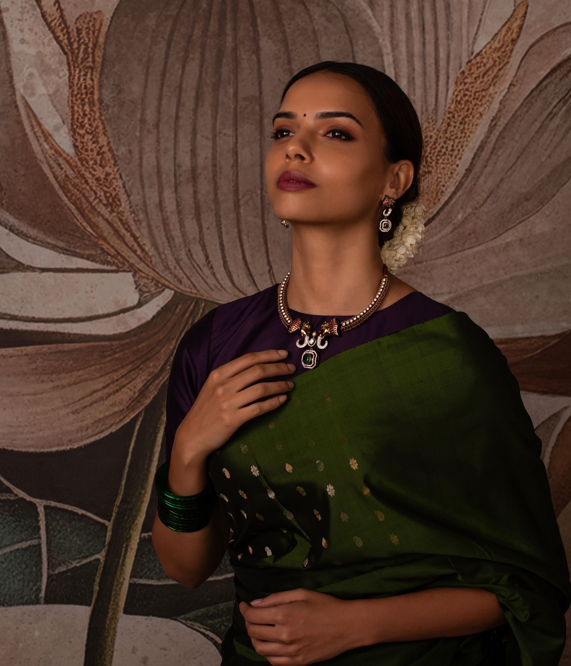 "Gold-plated silver Kanti necklace featuring an intricately designed elephant-shaped pendant. The elephant's ears are adorned with vibrant red cut stones, while its trunk is embellished with shimmering CZ stones. A striking green cut stone drop, encircled by CZ stones, adds an elegant finish to the design, making this necklace a perfect blend of tradition and sophistication.