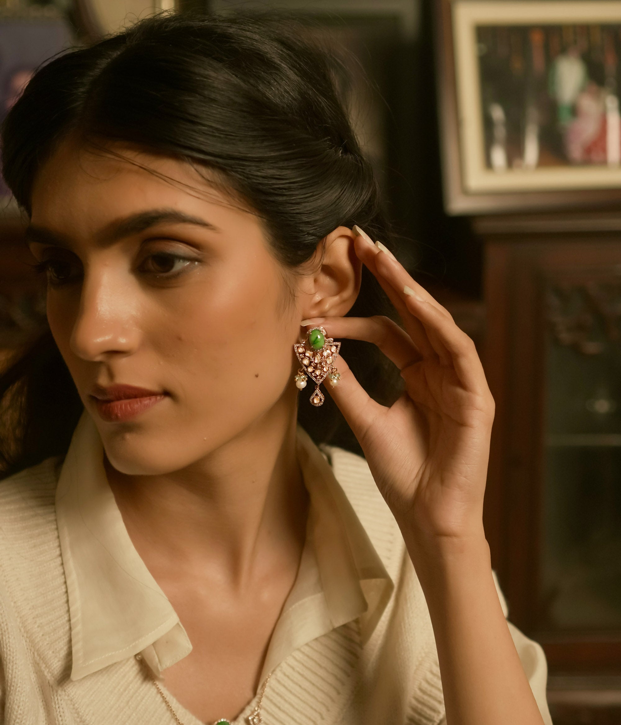 Triangular polki earrings with green gemstone, pearls, CZ accents, and tassel drop design.