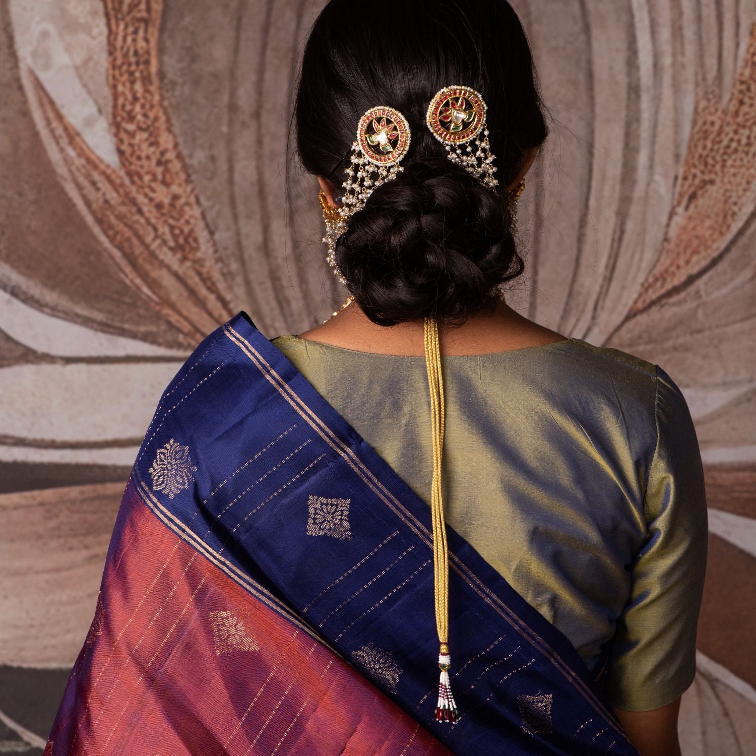 Gold-plated silver ear chain featuring a delicate string of Fresh Water Pearls, elegantly designed to connect to a hairpin at the end. The hairpin is adorned with Rubies, White Sapphires, and Emeralds, adding a regal touch. This exquisite piece enhances any traditional look with its graceful and sophisticated appeal.