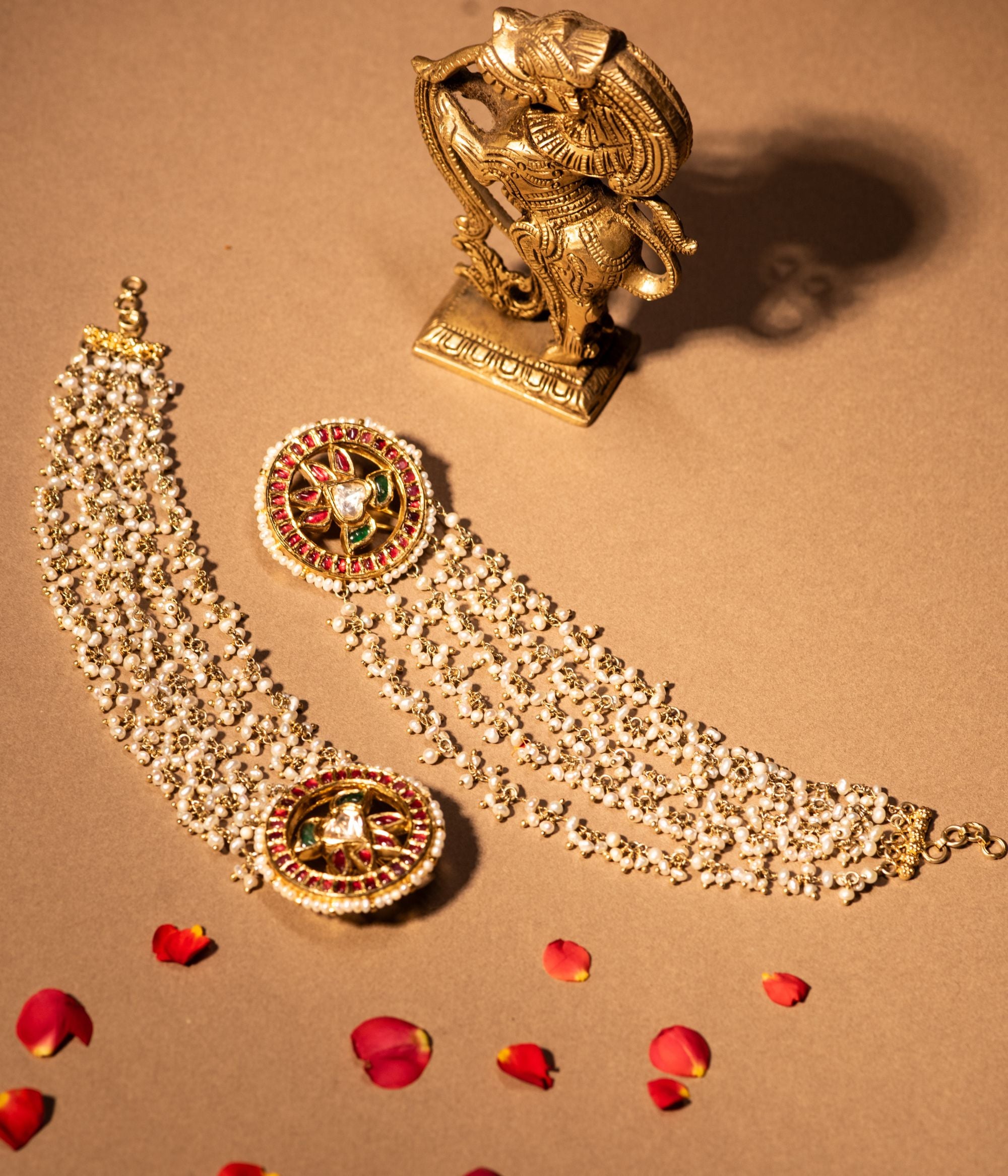 Gold-plated silver ear chain featuring a delicate string of Fresh Water Pearls, elegantly designed to connect to a hairpin at the end. The hairpin is adorned with Rubies, White Sapphires, and Emeralds, adding a regal touch. This exquisite piece enhances any traditional look with its graceful and sophisticated appeal.