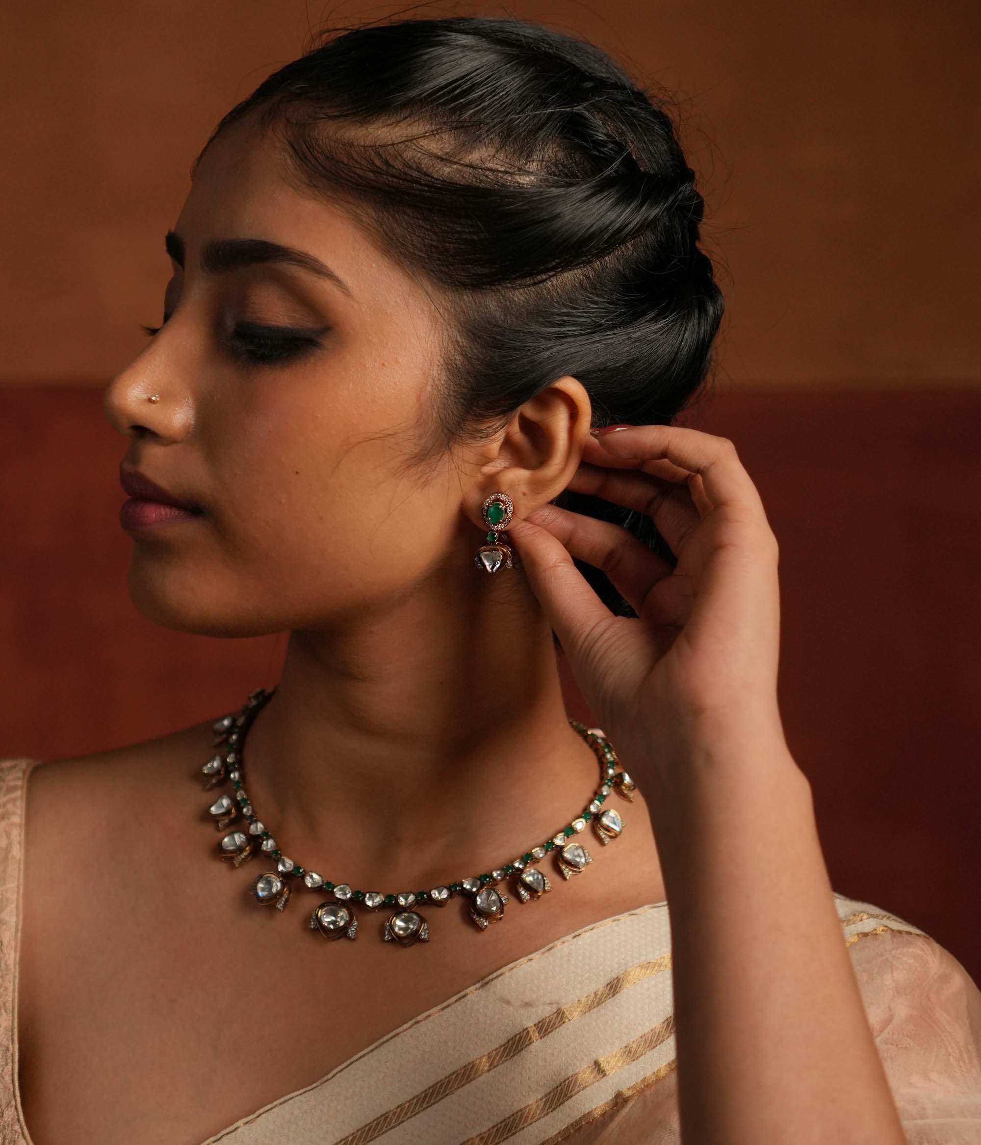 Elegant gold-plated silver drop earrings featuring a striking green spinel stone at the center, beautifully encased by shimmering CZ stones. The design is enhanced with a delicate Polki stone drop, also surrounded by CZ stones, adding a touch of timeless charm. A perfect blend of sophistication and elegance, making it an exquisite statement accessory.
