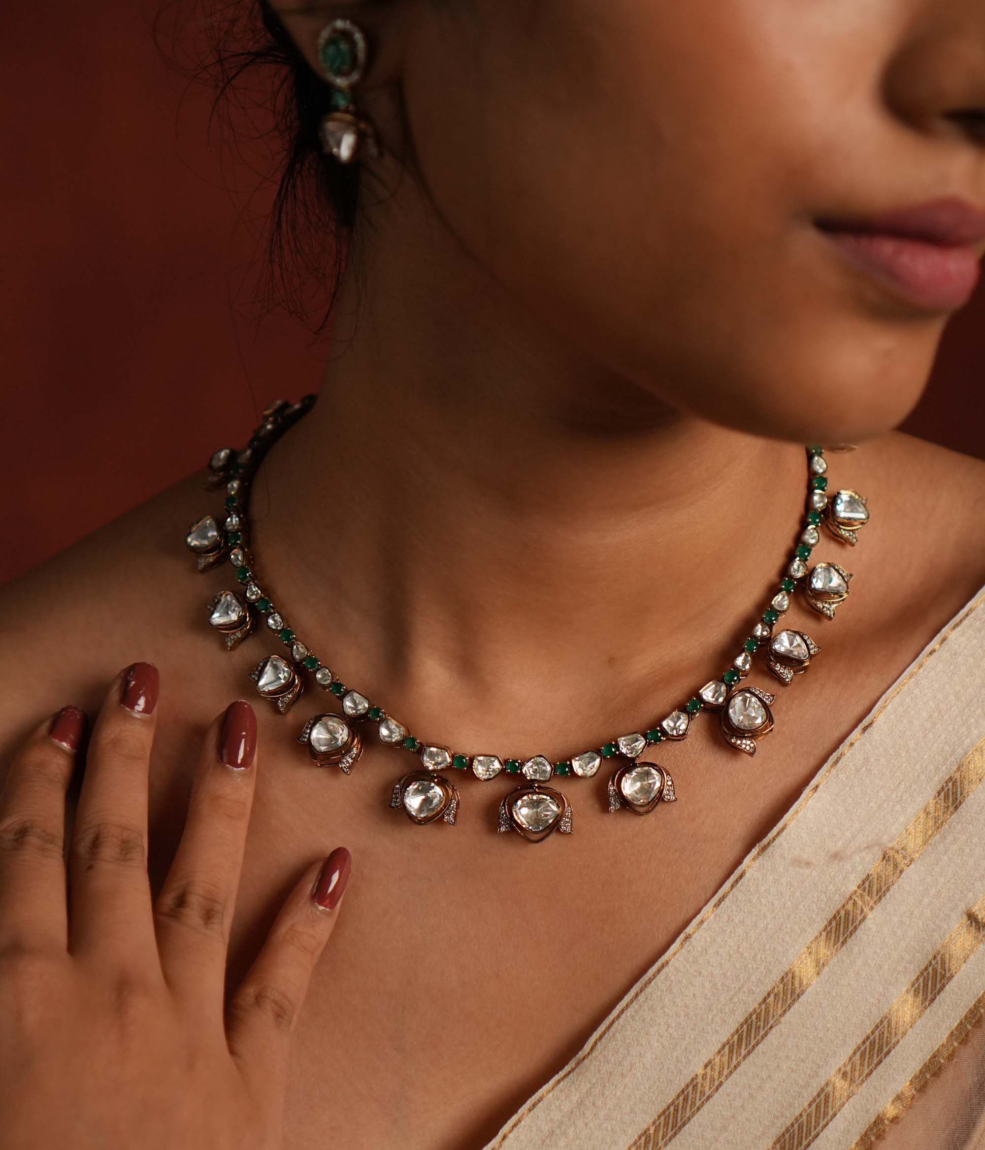 Elegant gold-plated silver drop necklace featuring a striking green spinel stone at the center, beautifully encased in shimmering CZ stones and Polki stones. The pendant is gracefully completed with a delicate Polki stone drop, also surrounded by CZ stones, adding a regal charm. This exquisite piece blends classic and modern elegance, making it a perfect statement accessory.
