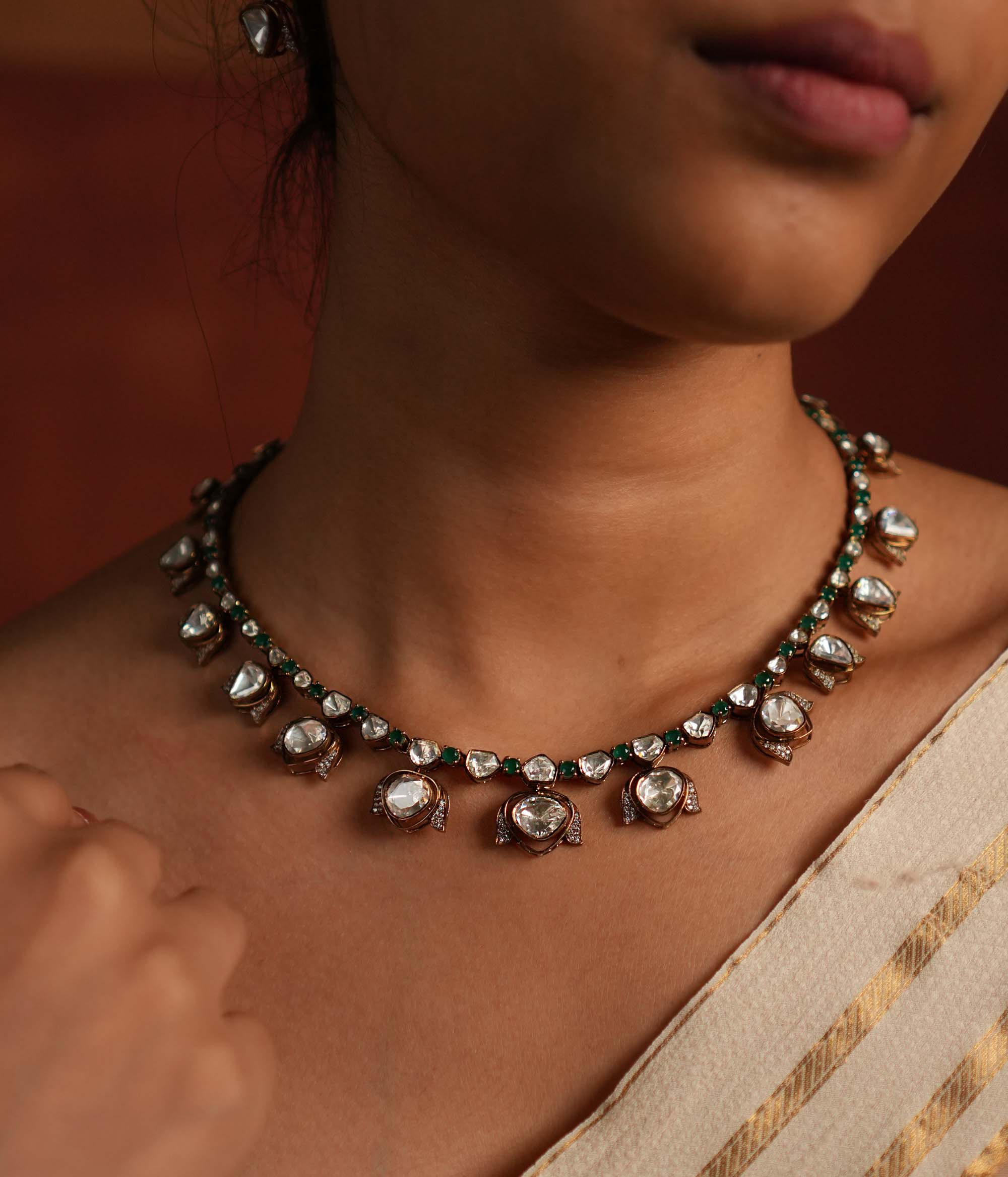 Elegant gold-plated silver drop necklace featuring a striking green spinel stone at the center, beautifully encased in shimmering CZ stones and Polki stones. The pendant is gracefully completed with a delicate Polki stone drop, also surrounded by CZ stones, adding a regal charm. This exquisite piece blends classic and modern elegance, making it a perfect statement accessory.