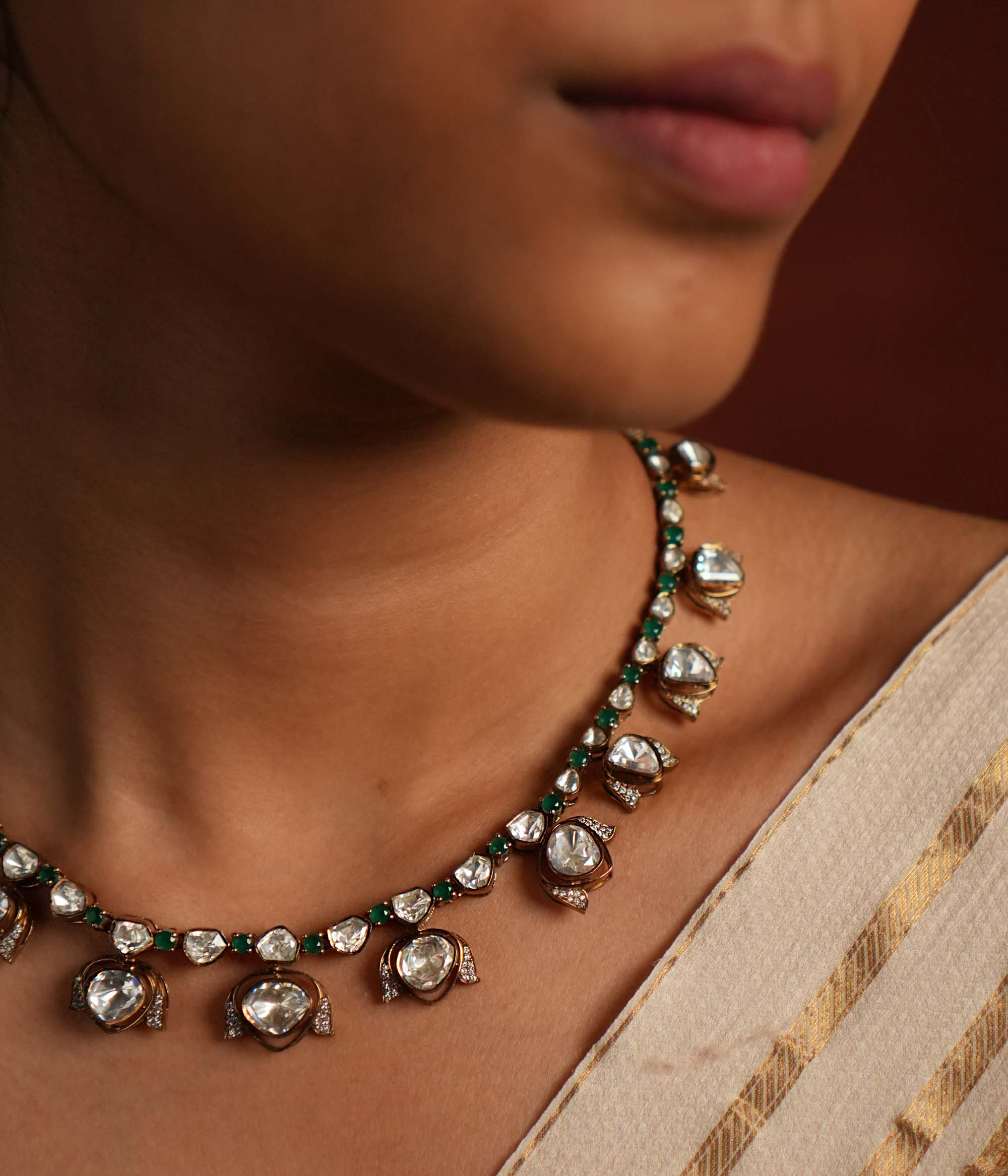 Elegant gold-plated silver drop necklace featuring a striking green spinel stone at the center, beautifully encased in shimmering CZ stones and Polki stones. The pendant is gracefully completed with a delicate Polki stone drop, also surrounded by CZ stones, adding a regal charm. This exquisite piece blends classic and modern elegance, making it a perfect statement accessory.