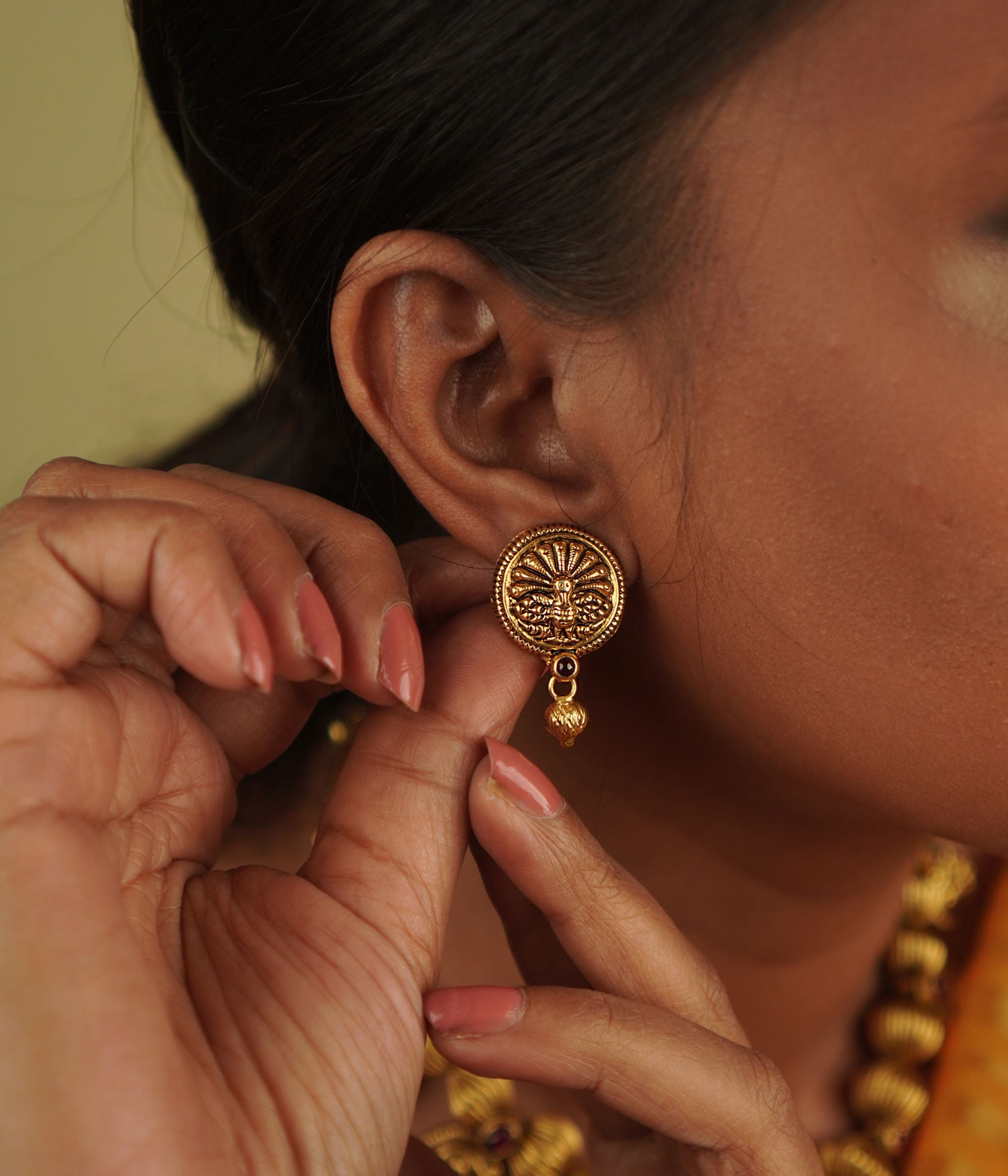 Rahni Earrings, elegantly crafted in antique gold-plated silver, seamlessly merge temple motifs with radiant red spinel, embodying both beauty and tradition.