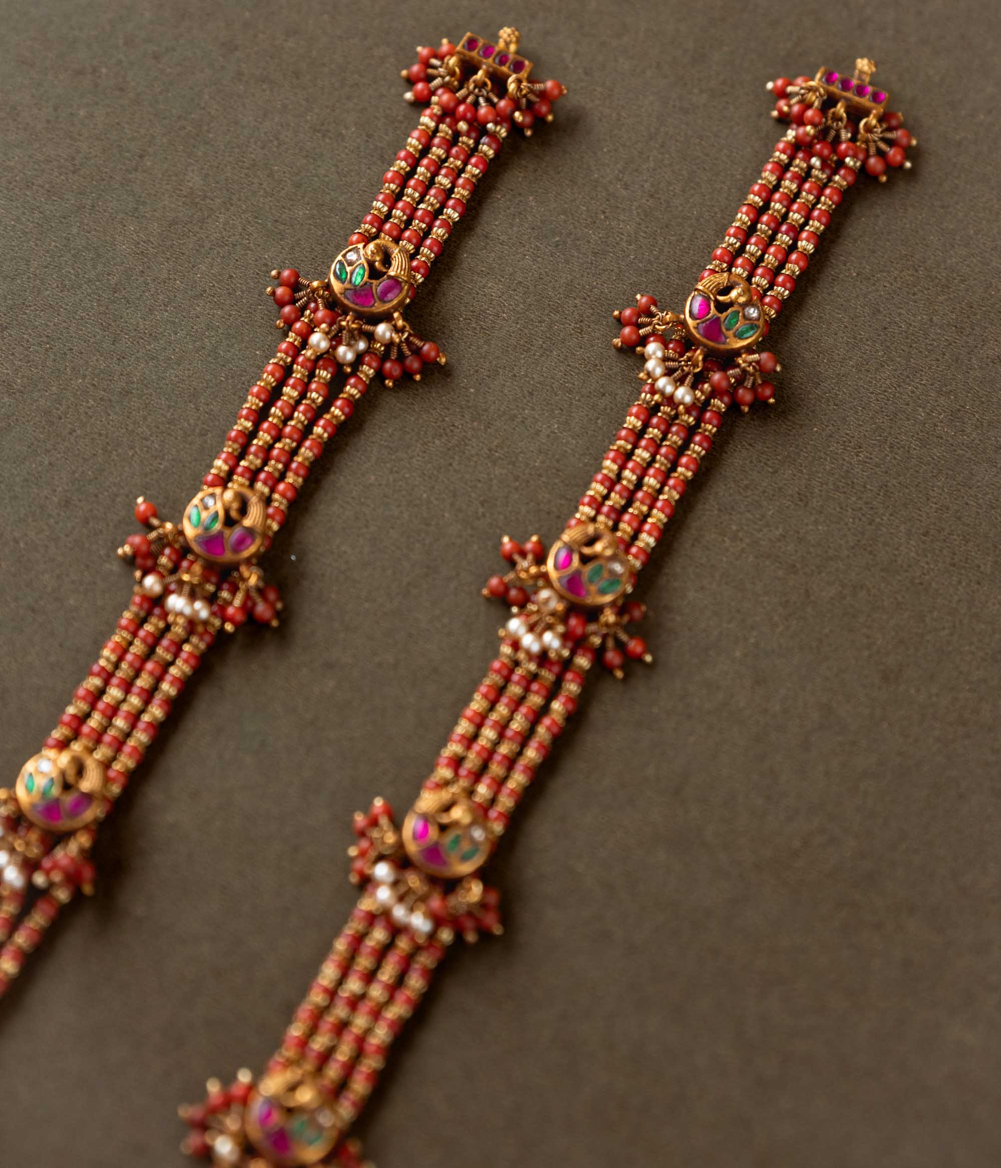 Ranjita Temple Beaded Chain featuring 92.5 sterling silver and 22 carat gold plating. The design includes vibrant coral-hued beads, intricate gold temple-inspired motifs, red, white, and green Kundan stones, and delicate pearls, combining tradition and artistry for a timeless, elegant look.