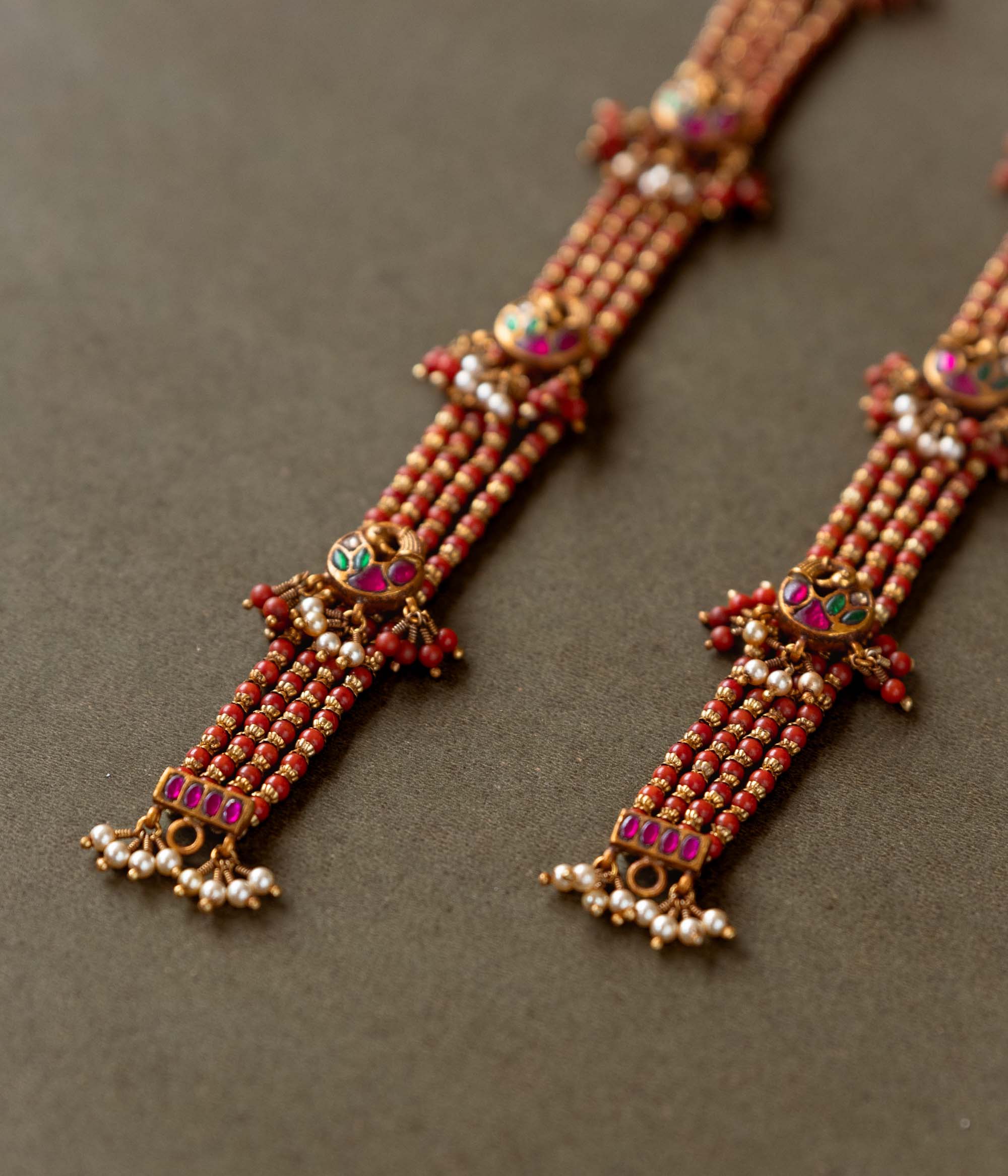Ranjita Temple Beaded Chain featuring 92.5 sterling silver and 22 carat gold plating. The design includes vibrant coral-hued beads, intricate gold temple-inspired motifs, red, white, and green Kundan stones, and delicate pearls, combining tradition and artistry for a timeless, elegant look.