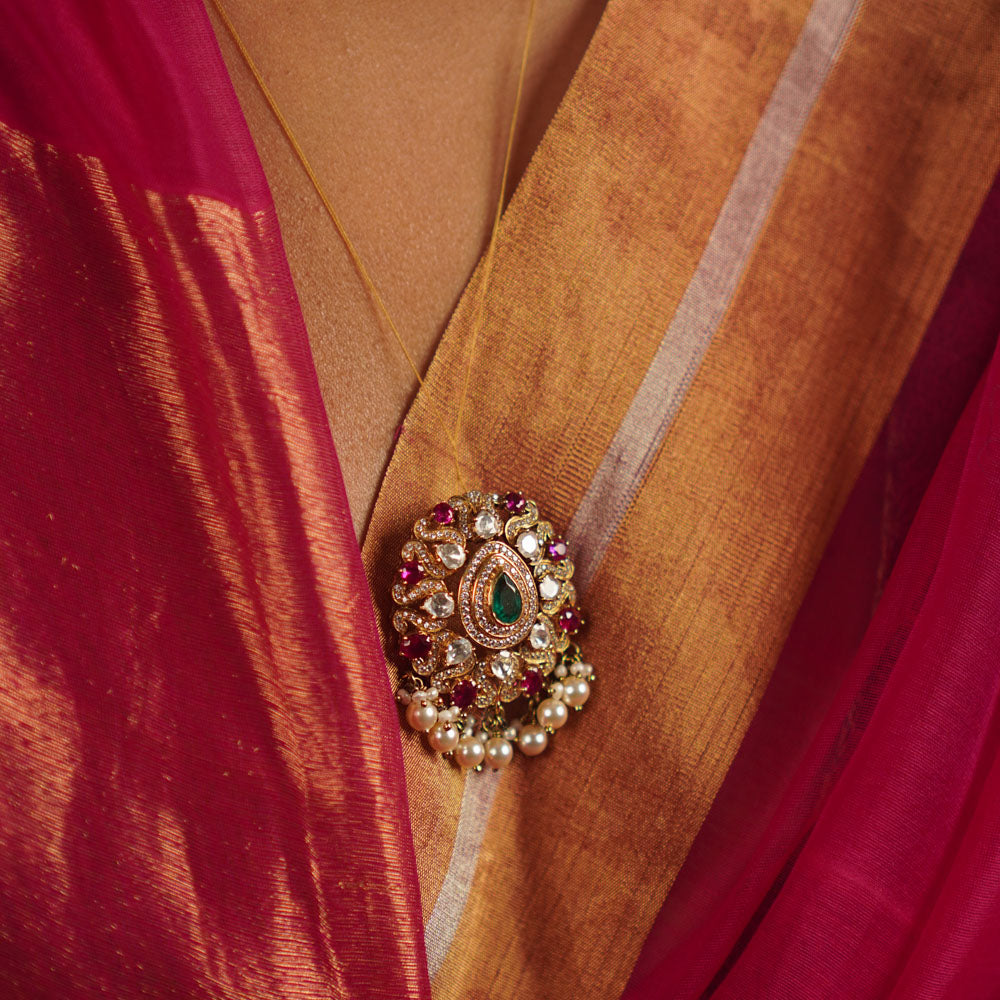 The Regis Pendant draws inspiration from the vast universe, capturing the brilliance of the night sky. Handcrafted in gold-plated silver, it features radiant polki stones, simulated rubies, and a shimmering moissanite halo, elegantly framed with delicate pearl accents. A celestial masterpiece that shines endlessly.