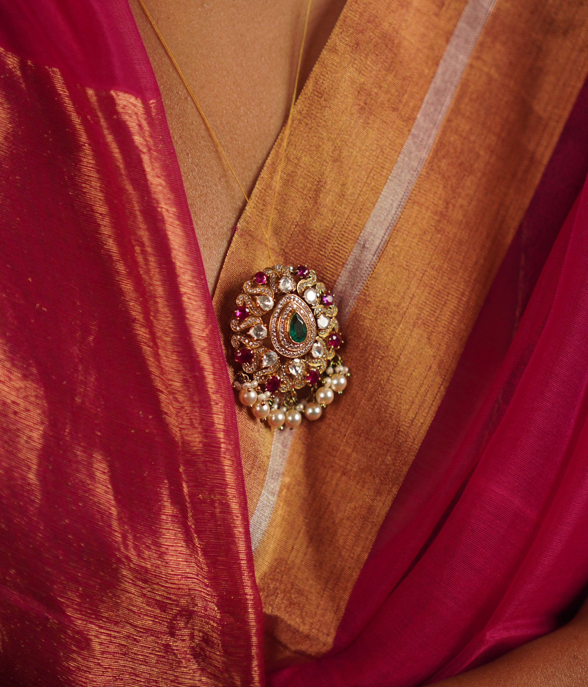 The Regis Pendant draws inspiration from the vast universe, capturing the brilliance of the night sky. Handcrafted in gold-plated silver, it features radiant polki stones, simulated rubies, and a shimmering moissanite halo, elegantly framed with delicate pearl accents. A celestial masterpiece that shines endlessly.