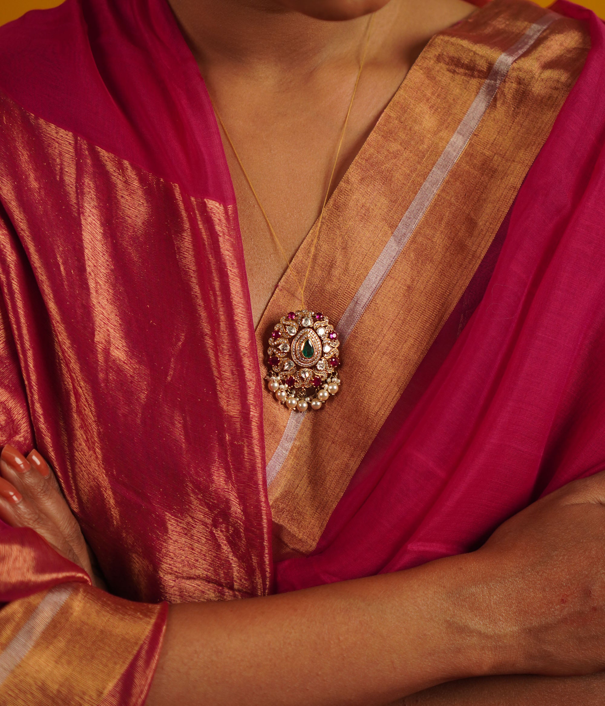 The Regis Pendant draws inspiration from the vast universe, capturing the brilliance of the night sky. Handcrafted in gold-plated silver, it features radiant polki stones, simulated rubies, and a shimmering moissanite halo, elegantly framed with delicate pearl accents. A celestial masterpiece that shines endlessly.