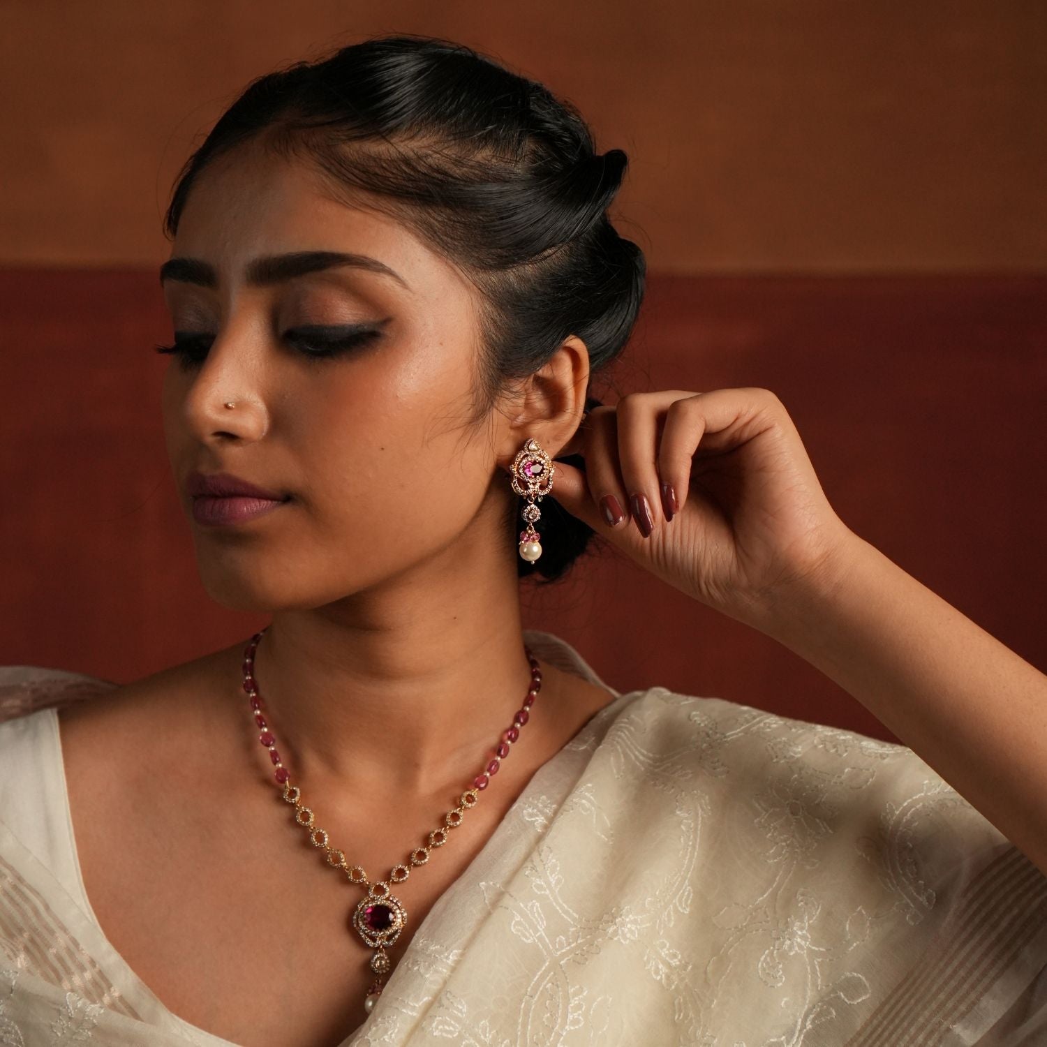 A dazzling gold-plated silver drop earring featuring a captivating Rose Quartz stone at the center, elegantly surrounded by shimmering CZ stones. The graceful drop showcases a radiant Polki stone, complemented by a delicate white pearl and soft pink beads, adding a touch of sophistication and charm. Perfect for an elegant and timeless look.