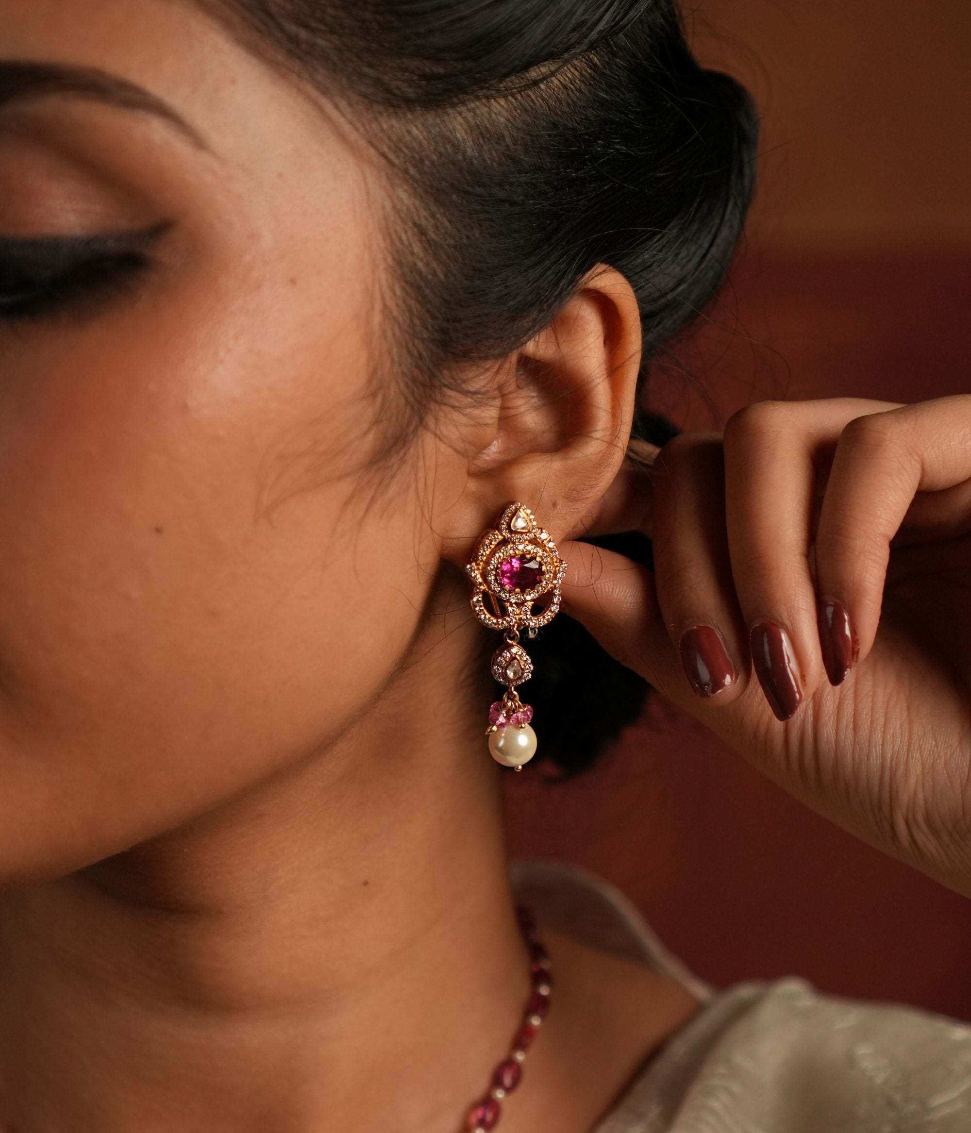 A dazzling gold-plated silver drop earring featuring a captivating Rose Quartz stone at the center, elegantly surrounded by shimmering CZ stones. The graceful drop showcases a radiant Polki stone, complemented by a delicate white pearl and soft pink beads, adding a touch of sophistication and charm. Perfect for an elegant and timeless look.