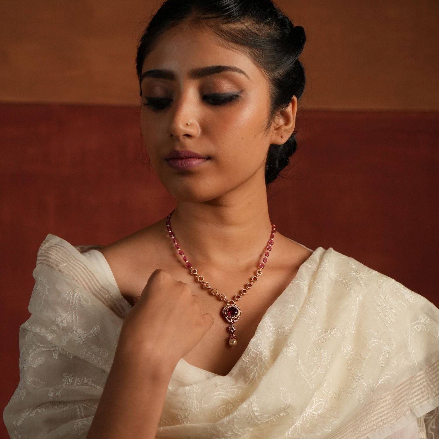 A dazzling gold-plated silver necklace featuring a captivating Rose Quartz stone at the center, elegantly surrounded by shimmering CZ stones. The pendant showcases a radiant Polki stone, complemented by delicate white pearls and soft pink beads, adding a touch of sophistication and charm. Perfect for an elegant and timeless look.