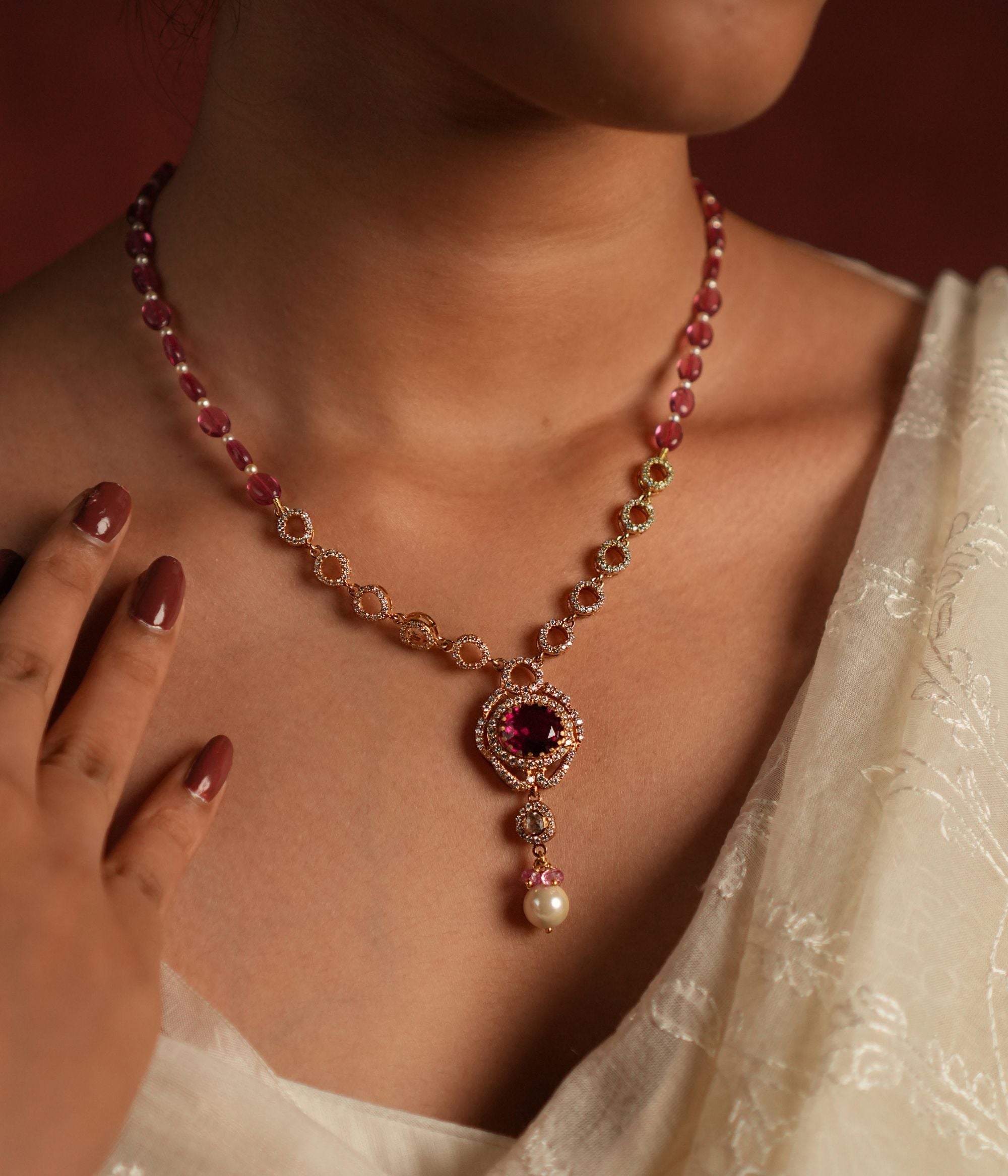 A dazzling gold-plated silver necklace featuring a captivating Rose Quartz stone at the center, elegantly surrounded by shimmering CZ stones. The pendant showcases a radiant Polki stone, complemented by delicate white pearls and soft pink beads, adding a touch of sophistication and charm. Perfect for an elegant and timeless look.