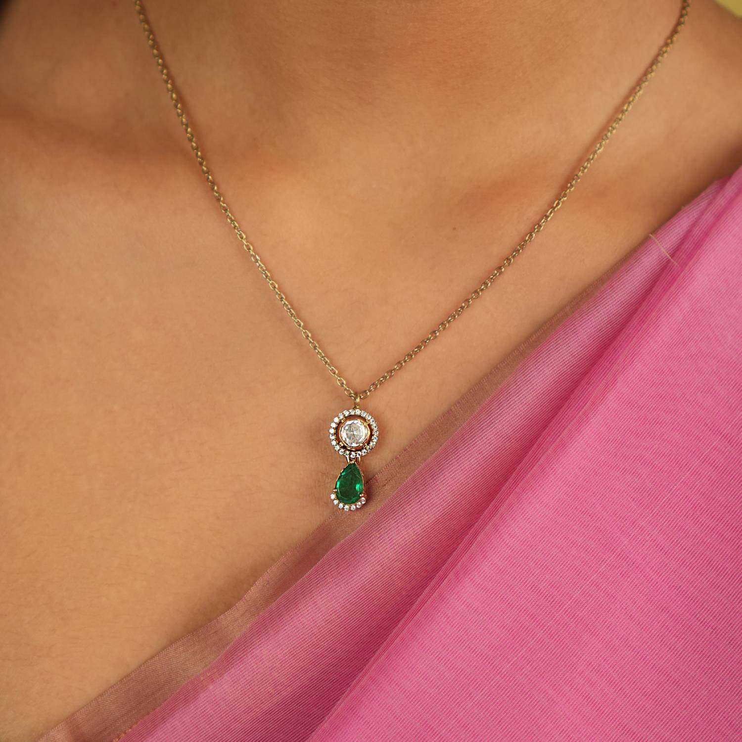 This pendant features dazzling Polki stones encircling shimmering CZ accents, gracefully completed with a radiant green gemstone drop, exuding timeless elegance.