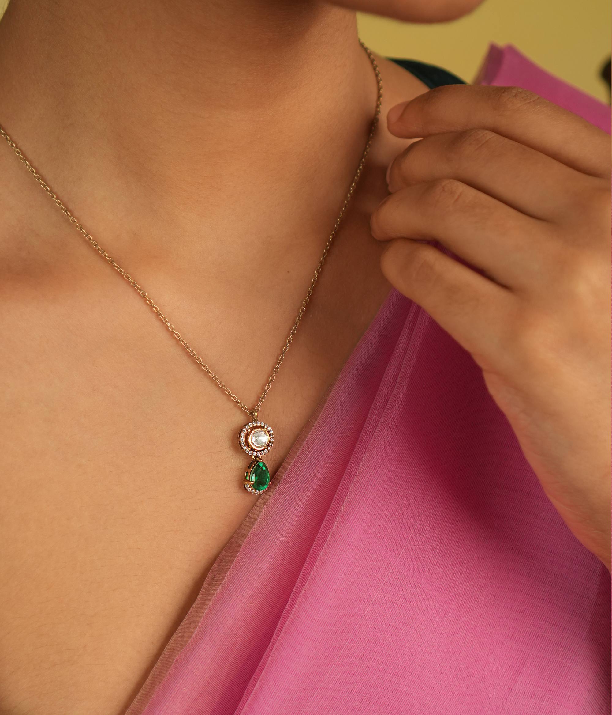 This pendant features dazzling Polki stones encircling shimmering CZ accents, gracefully completed with a radiant green gemstone drop, exuding timeless elegance.