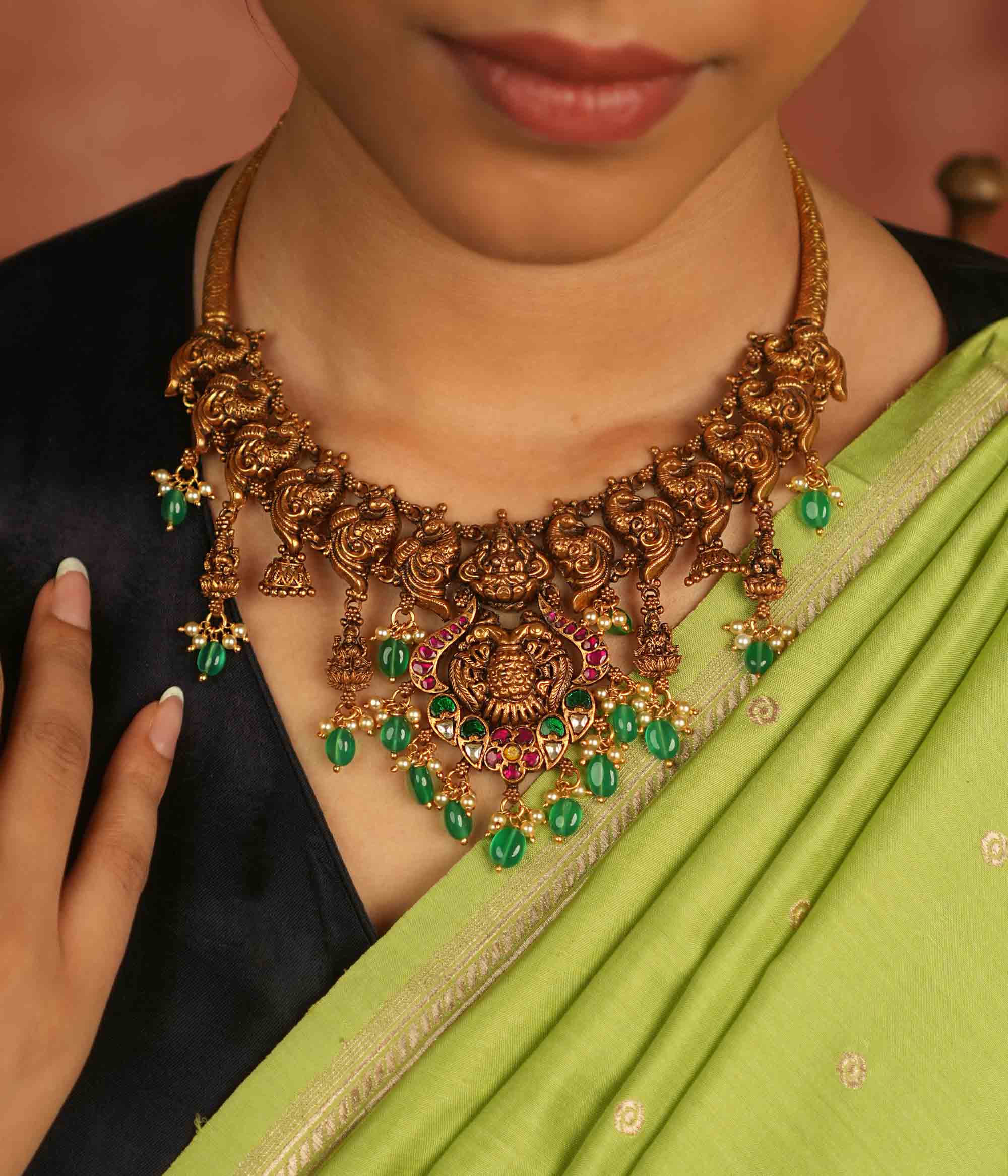 Temple whispers reborn! Antique gold-plated necklace adorned with goddess motifs, kundan stones, pearls, and green beads, echoing divine elegance and timeless heritage.