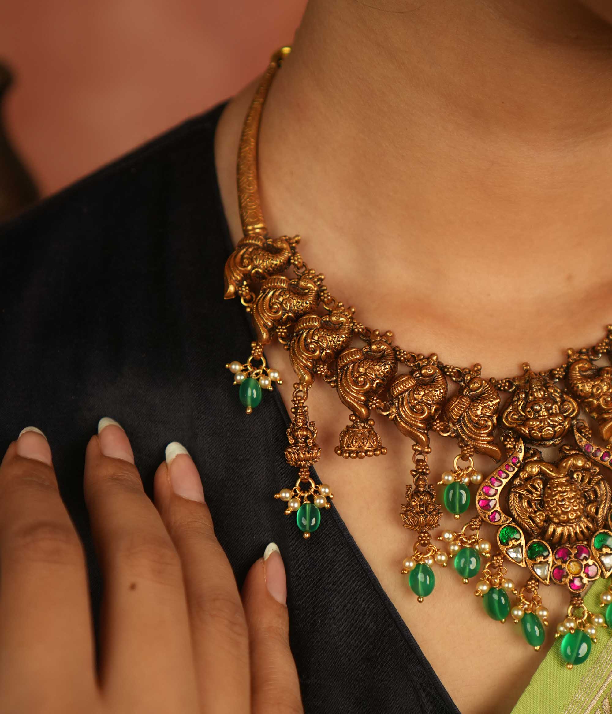 Temple whispers reborn! Antique gold-plated necklace adorned with goddess motifs, kundan stones, pearls, and green beads, echoing divine elegance and timeless heritage.