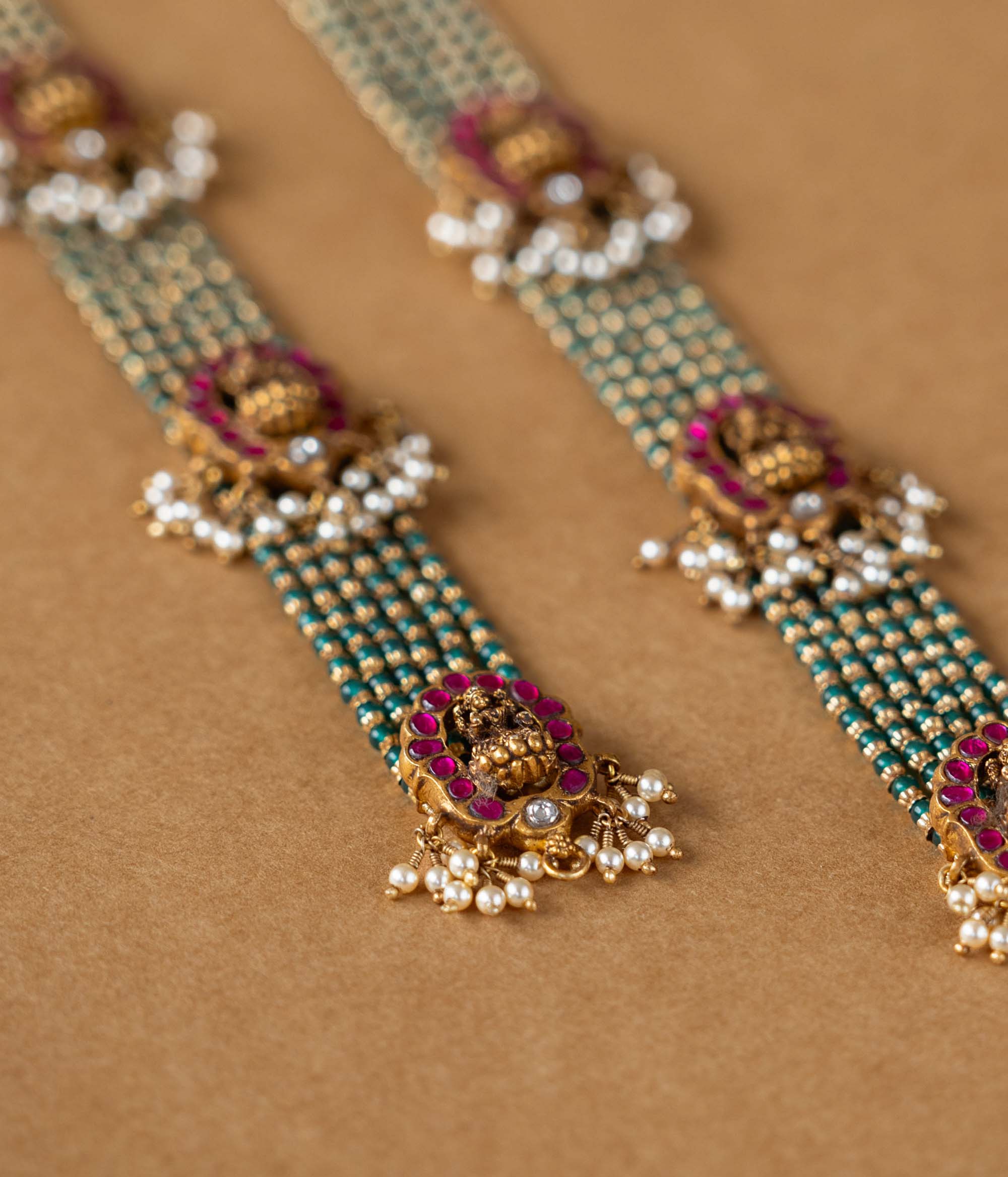 Elegant temple-style beaded chain featuring 92.5 sterling silver, 22k gold plating, red and white Kundan stones, and pearls.
