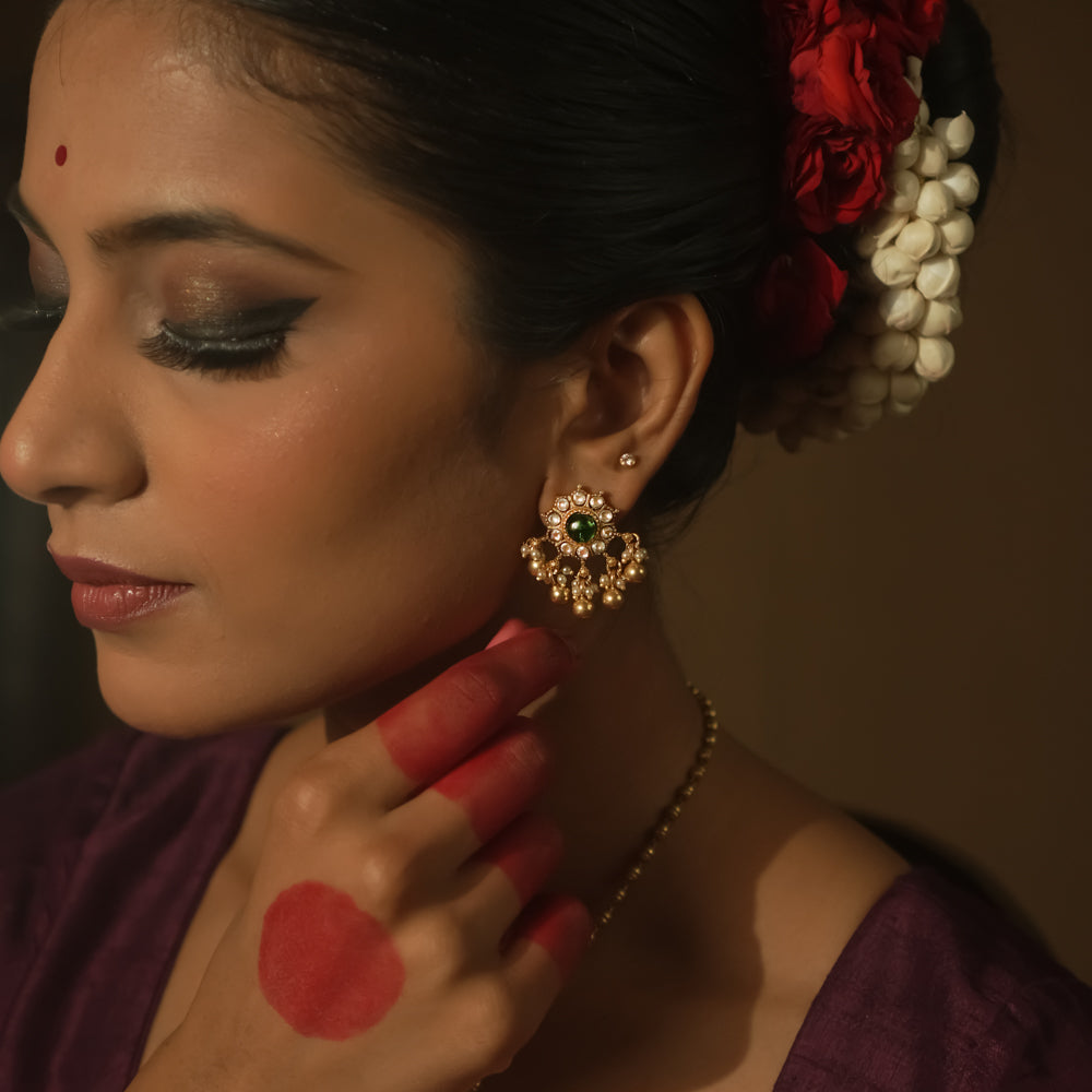 Gold-plated silver filigree earrings with a central green Kundan stone.