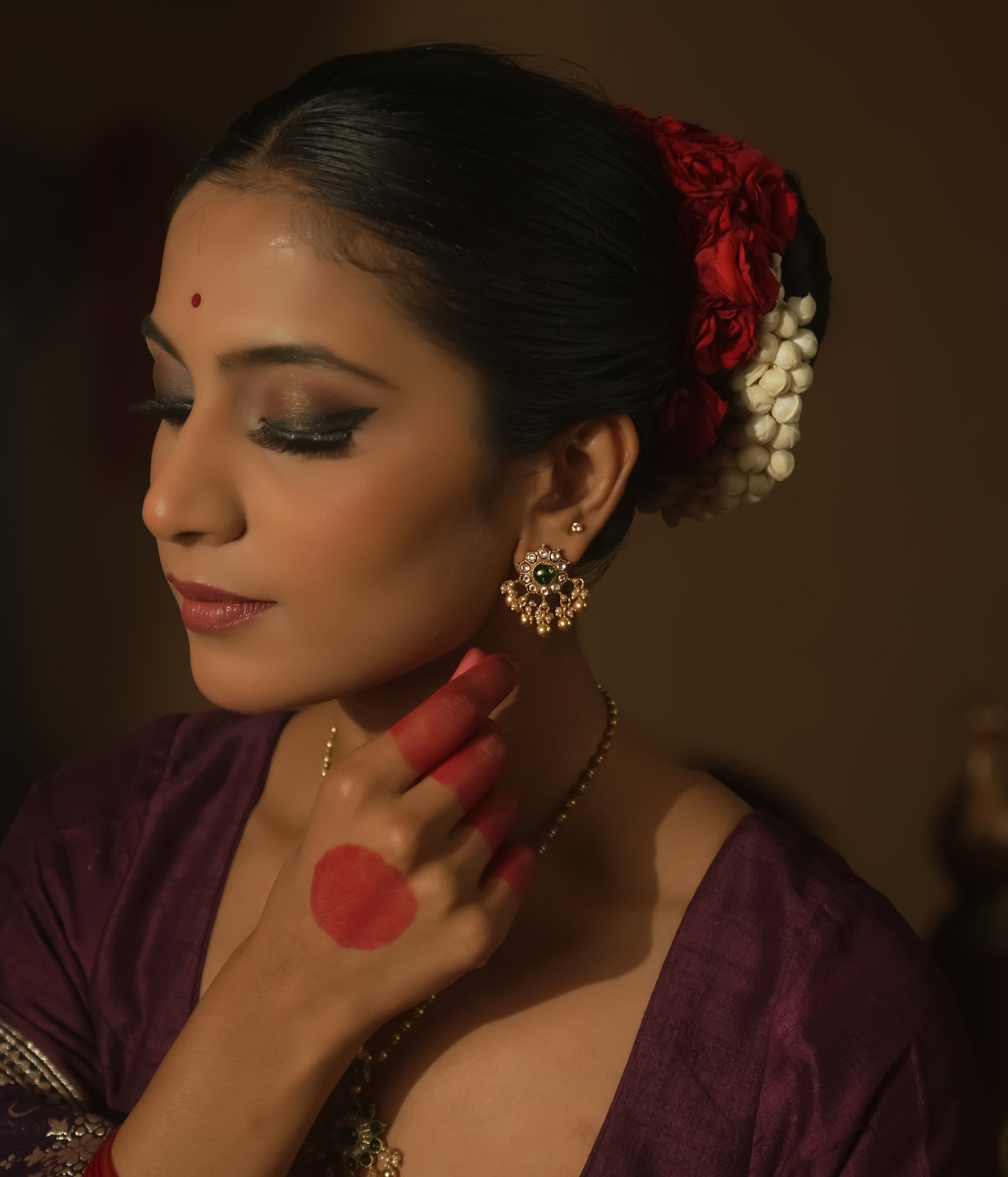 Gold-plated silver filigree earrings with a central green Kundan stone.