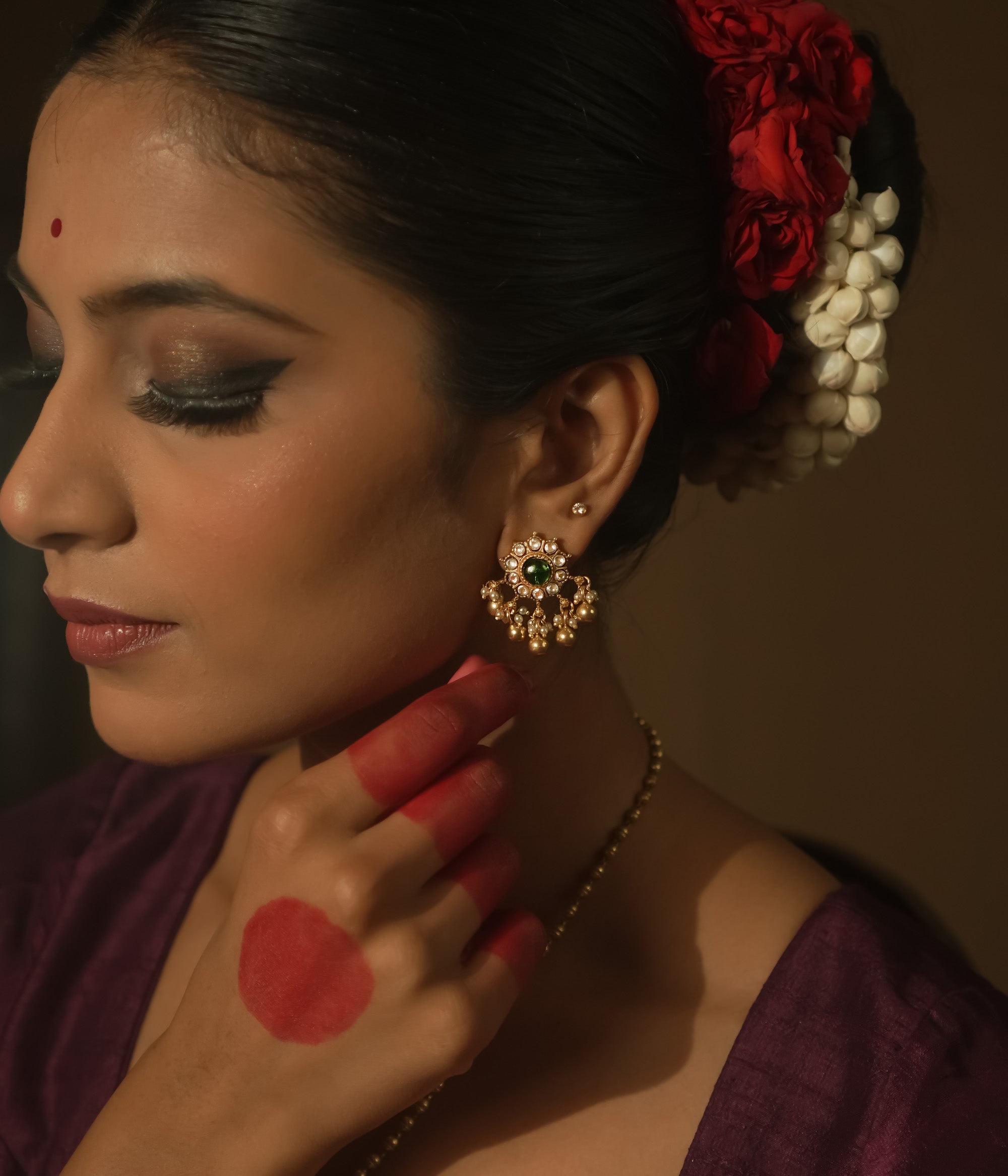 Gold-plated silver filigree earrings with a central green Kundan stone.