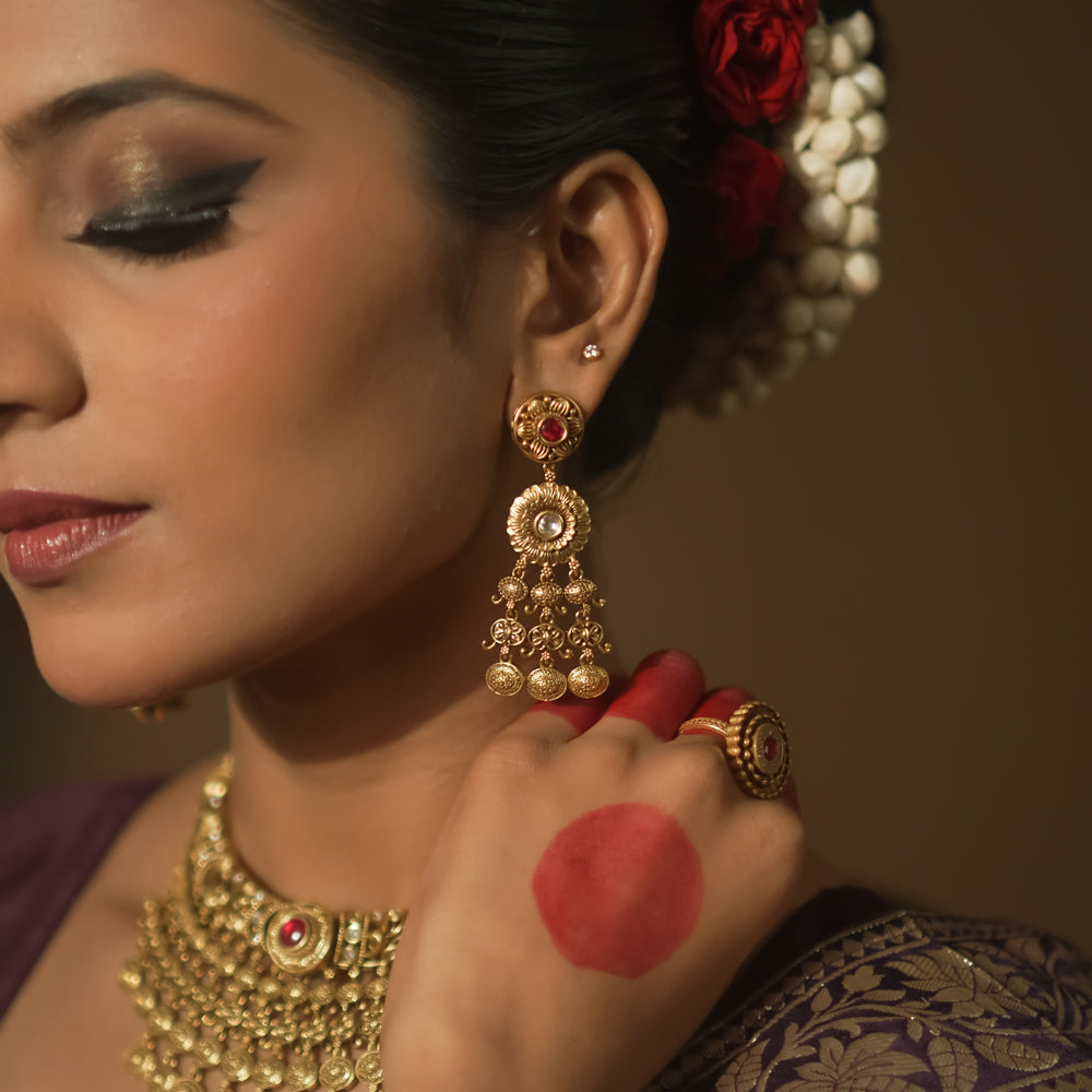 Gold-plated silver dangling earrings with a crimson gem, intricate loops, and tiny bells.