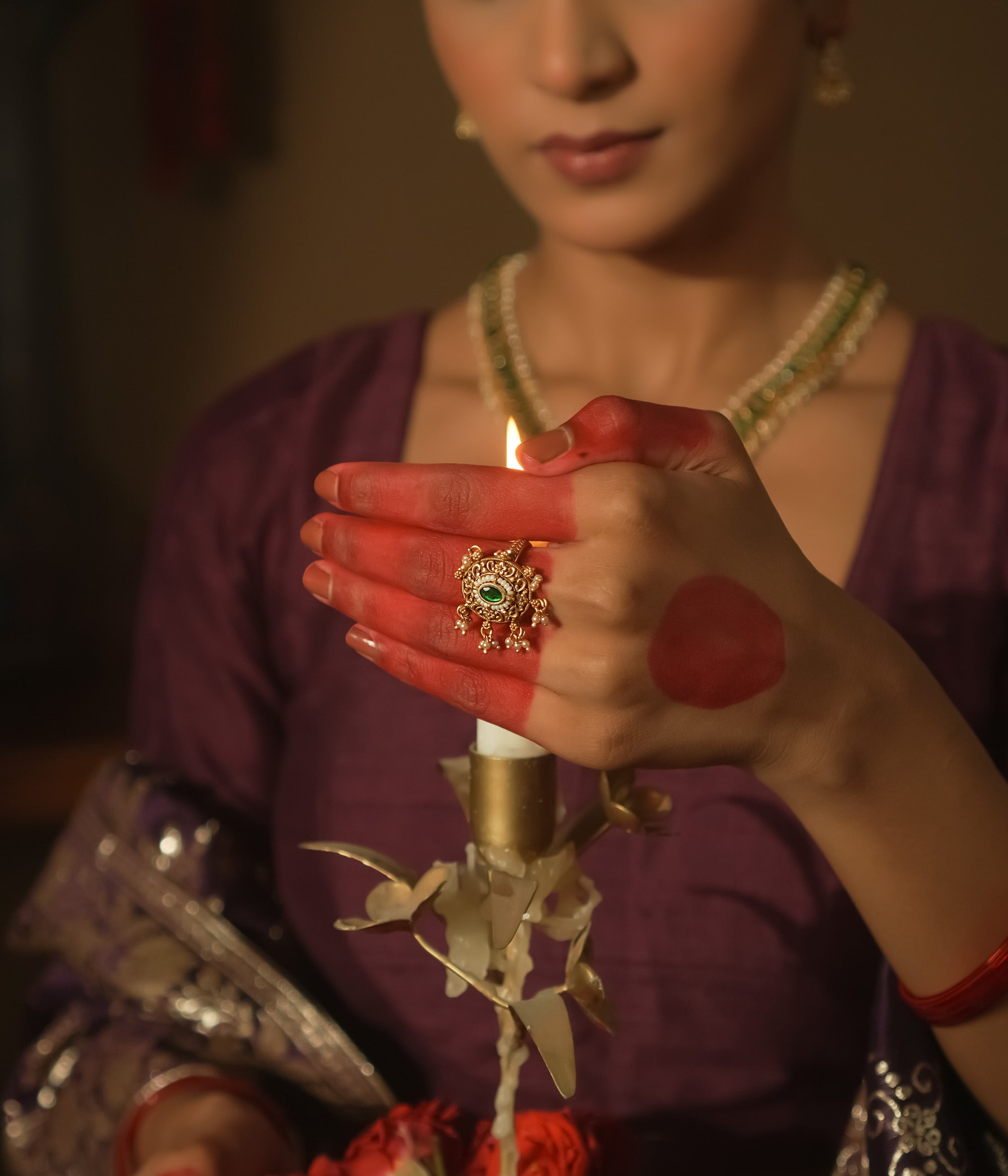Gold ring with a sun motif, a central emerald Kundan, and filigree petals.