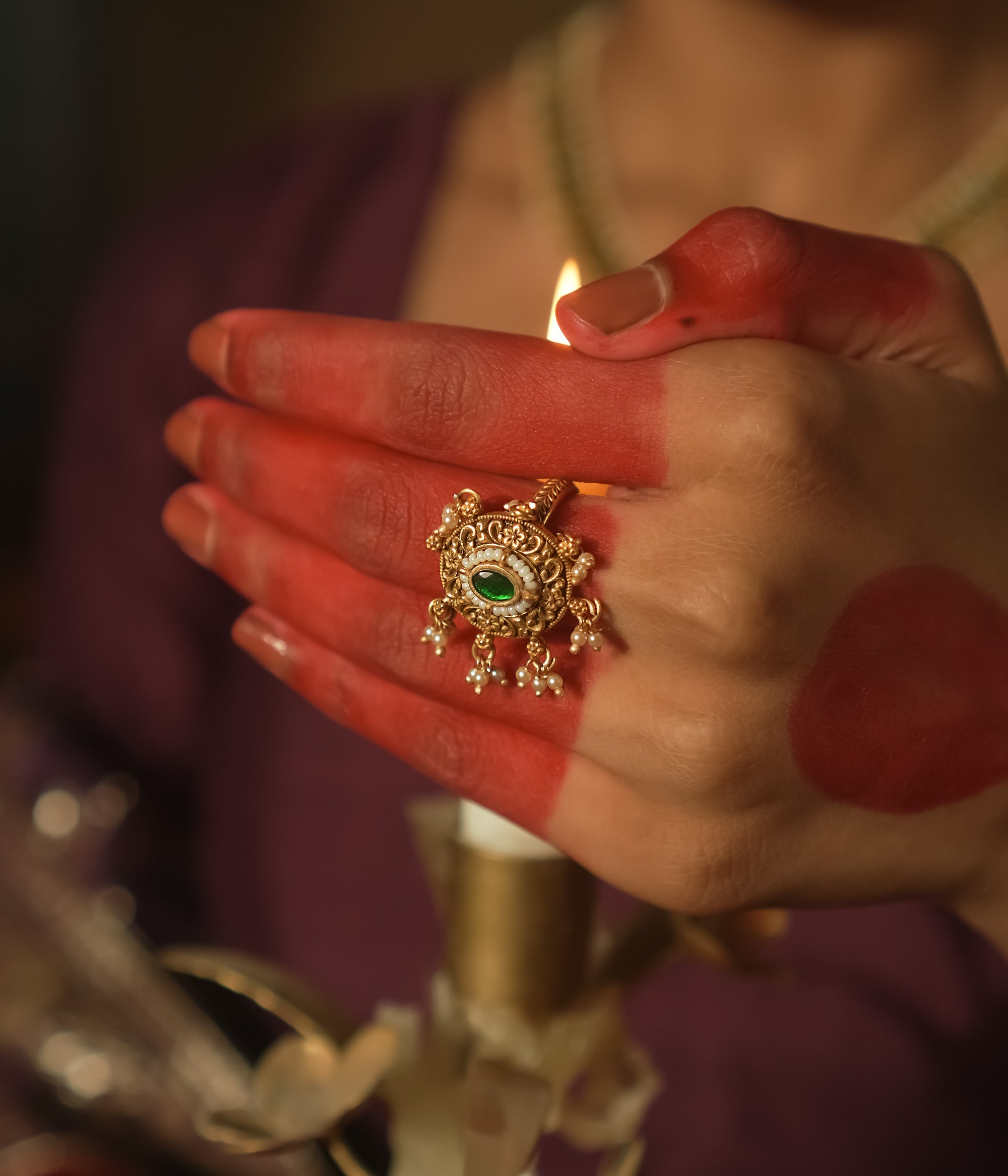 Gold ring with a sun motif, a central emerald Kundan, and filigree petals.