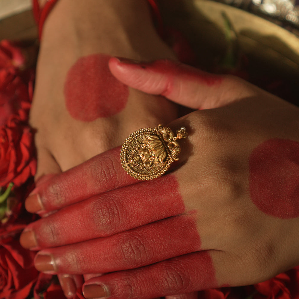 Gold ring with a central Lakshmi goddess motif and beaded edges.