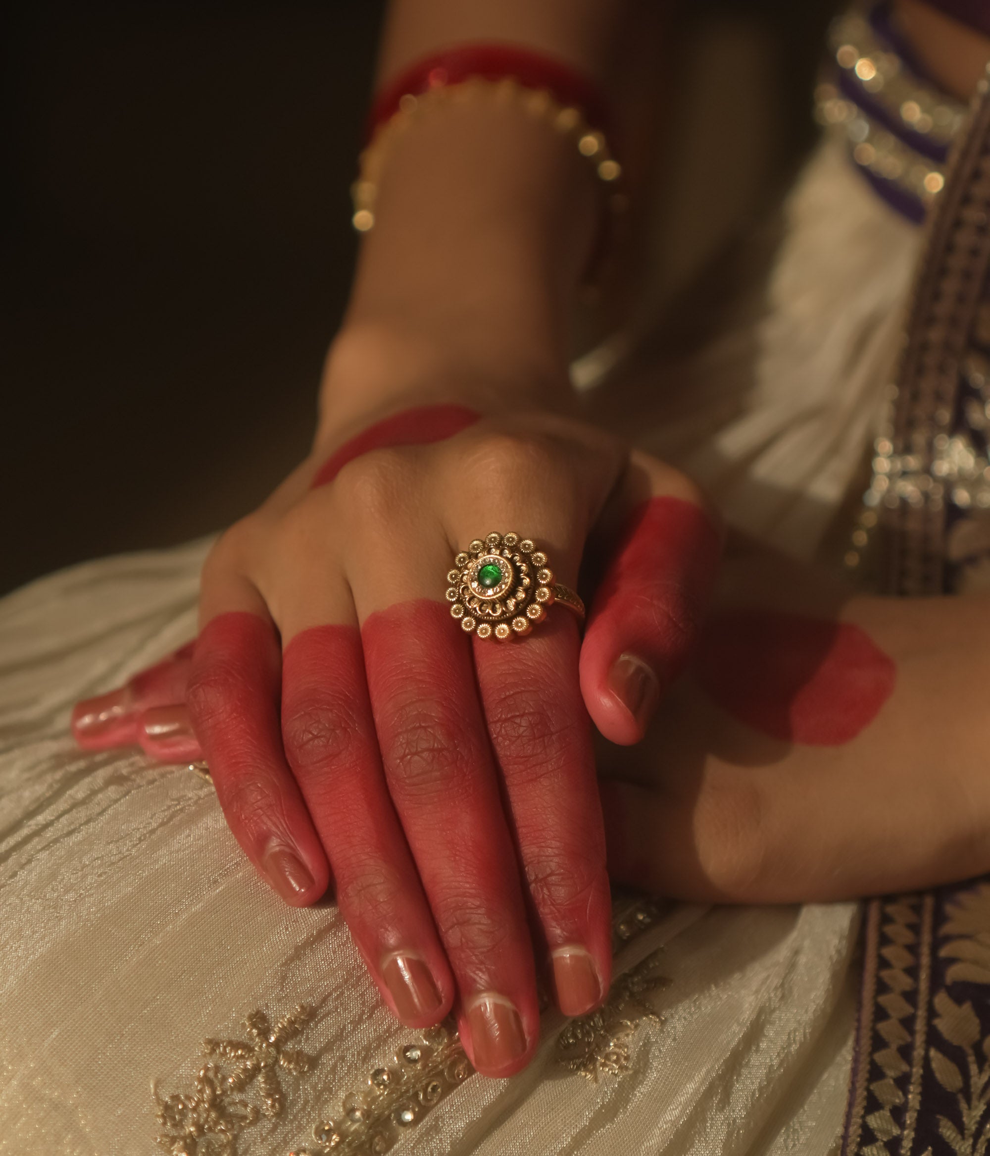 Gold-plated silver ring with a central green gem and a speckled dot pattern.